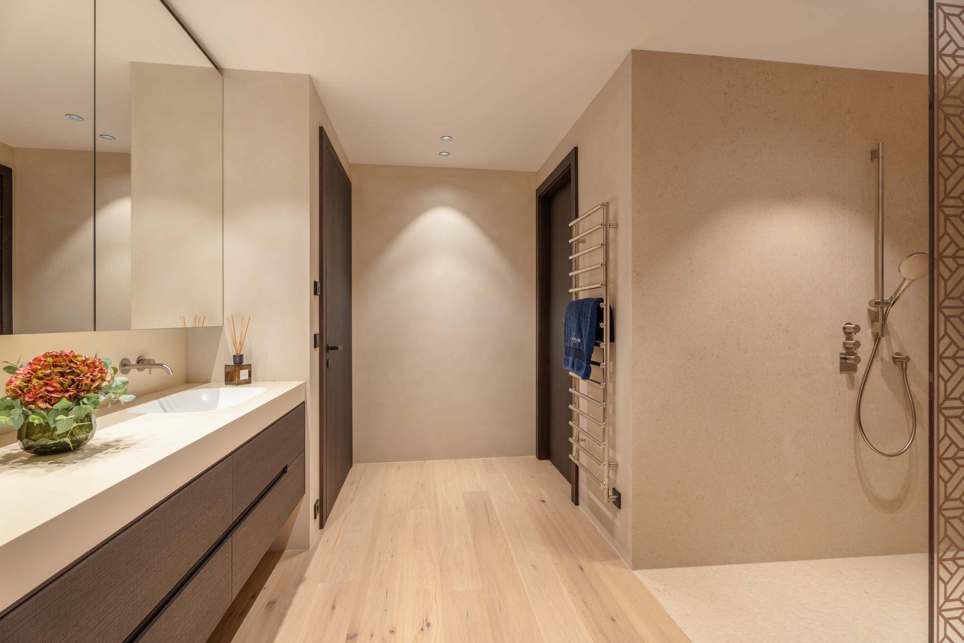 Elegantes Badezimmer mit modernem Waschtisch, begehbarer Dusche und beheiztem Handtuchhalter.