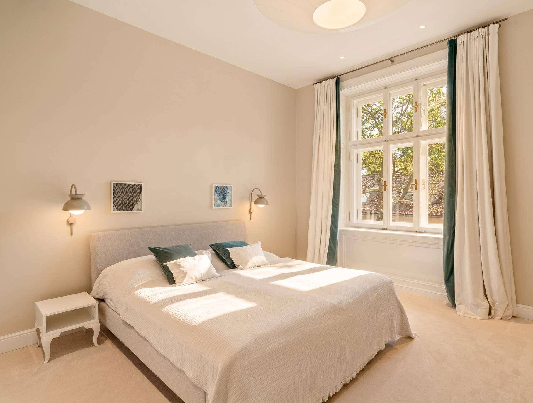 Gemütliches Schlafzimmer mit Doppelbett, Nachttischen und großem Fenster mit Blick ins Grüne.