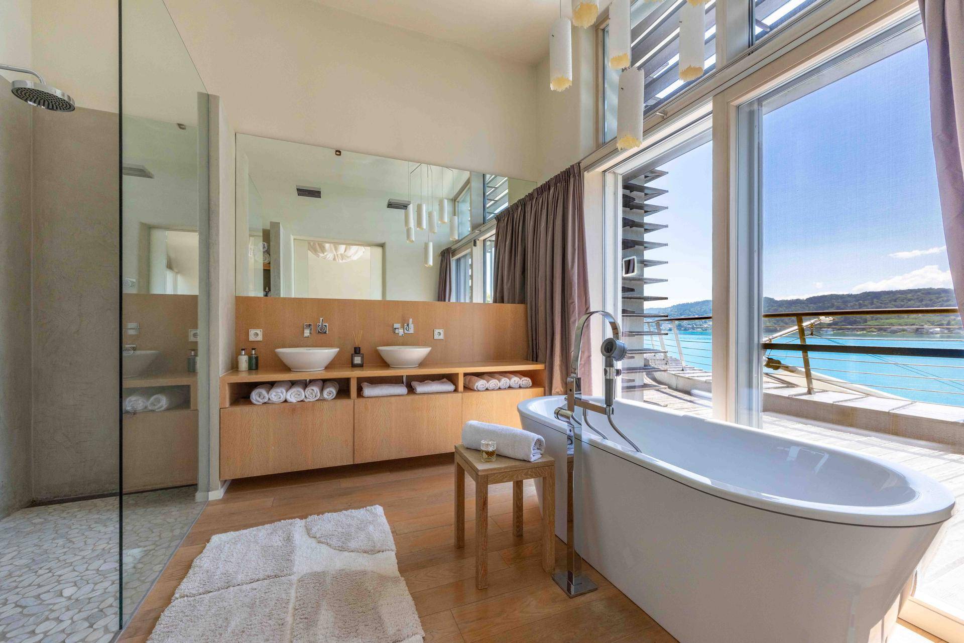 Luxuriöses Badezimmer mit freistehender Badewanne, begehbarer Dusche und Doppelwaschbecken mit Seeblick.