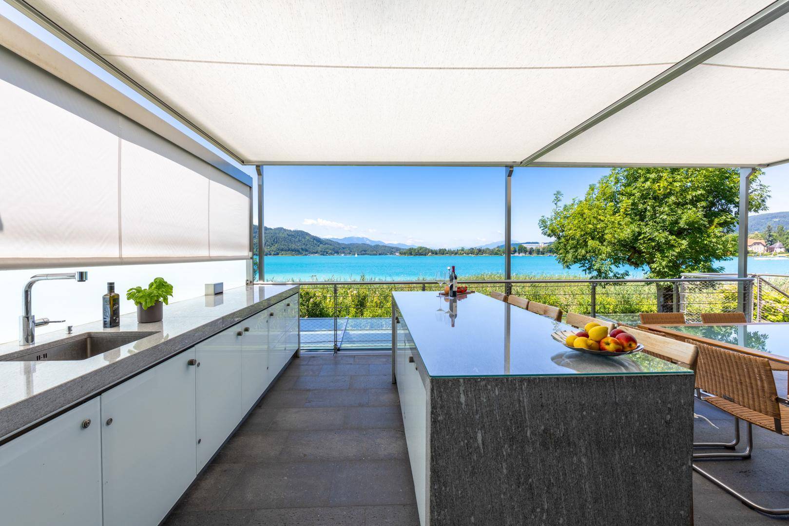 Moderne Außenküche auf der Terrasse mit Spüle, Arbeitsfläche und Panoramablick auf den See.
