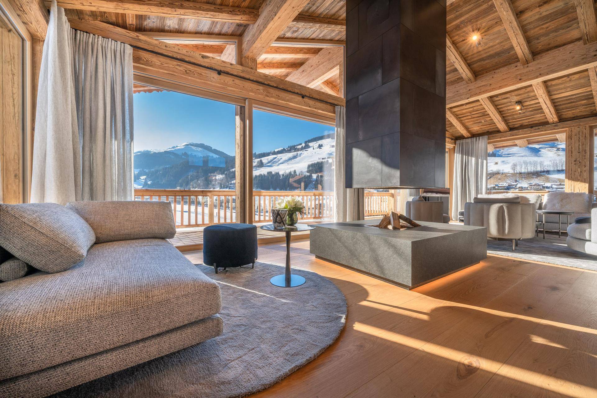 Gemütlicher Wohnbereich mit modernem Kamin und weitem Blick auf die winterliche Bergwelt.