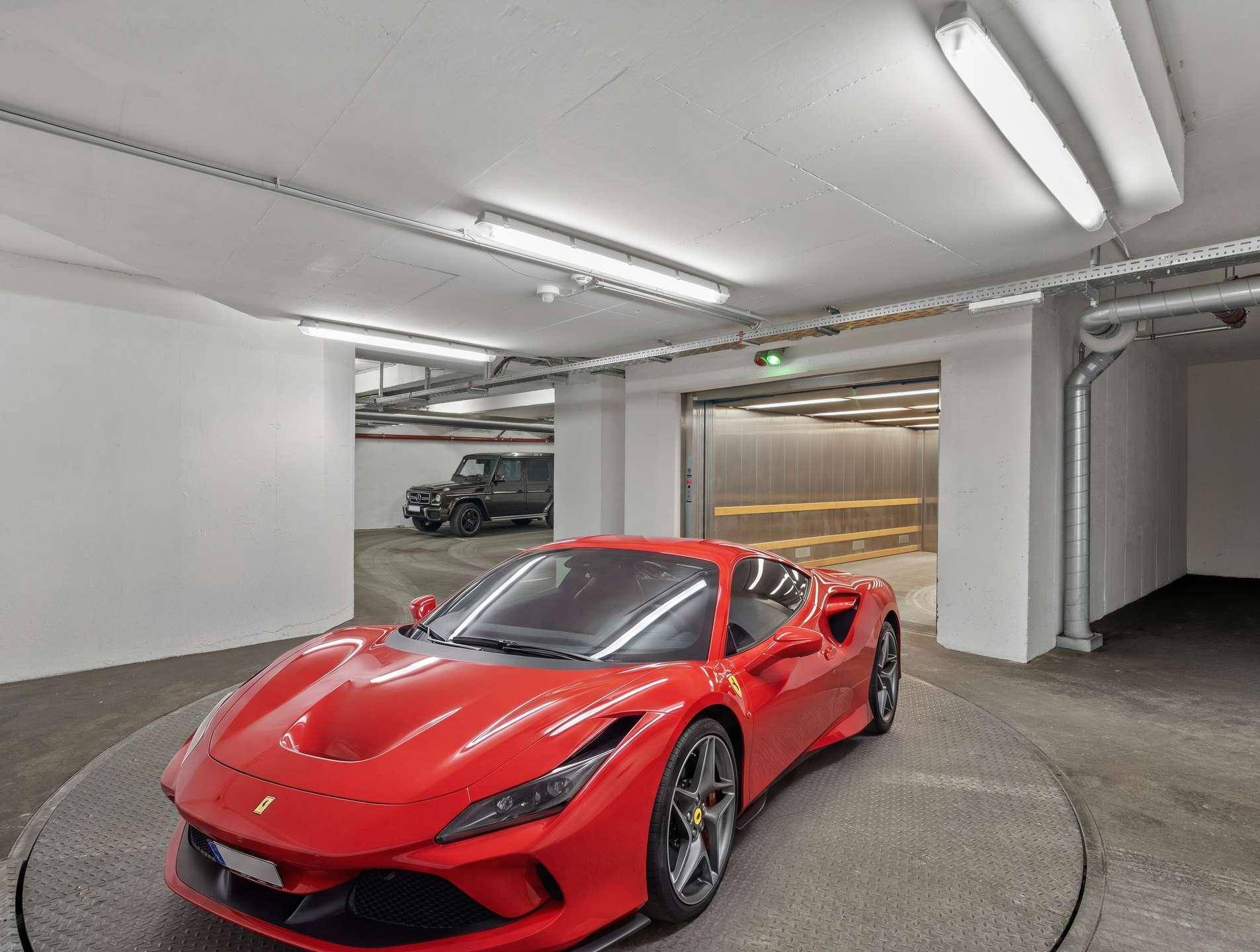 Tiefgarage mit einem roten Sportwagen auf einer Drehplattform und einem Aufzug.