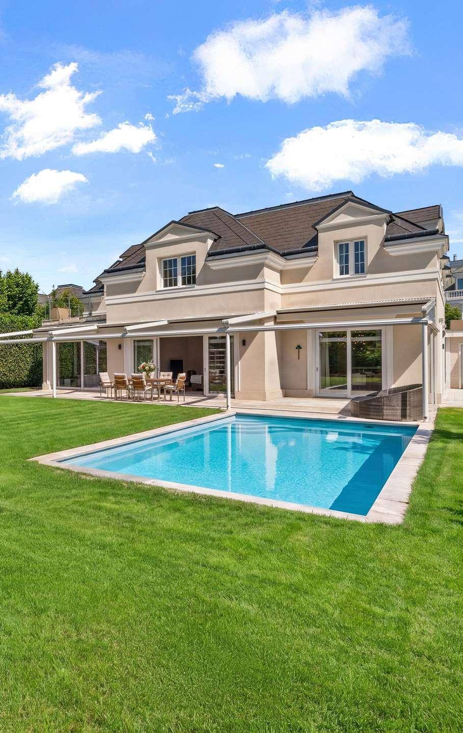 Großzügiger Gartenbereich mit privatem Pool, weitläufiger Rasenfläche und überdachter Terrasse.