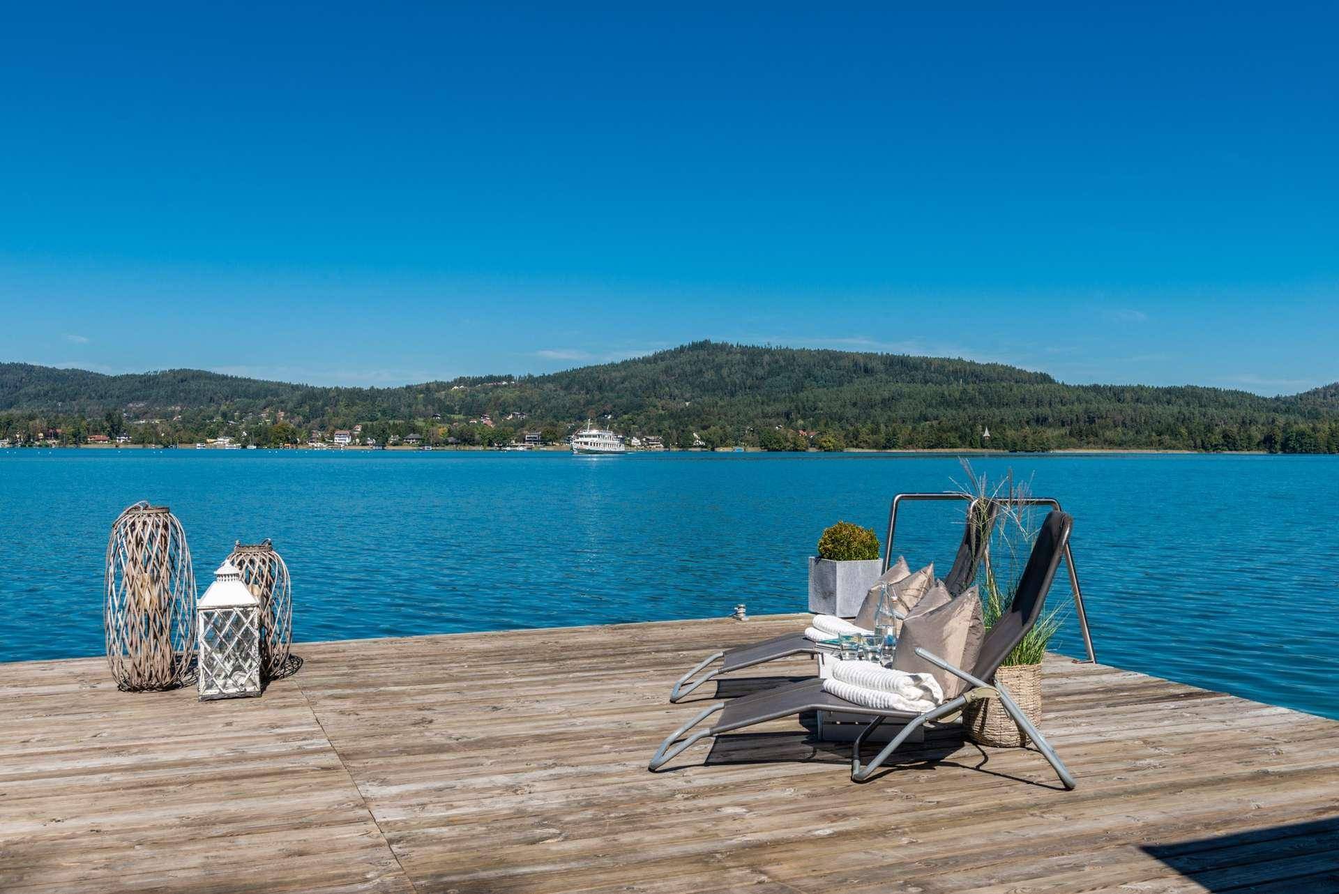 Privater Holzsteg am See mit Liegestühlen, perfekt zum Entspannen am Wasser.