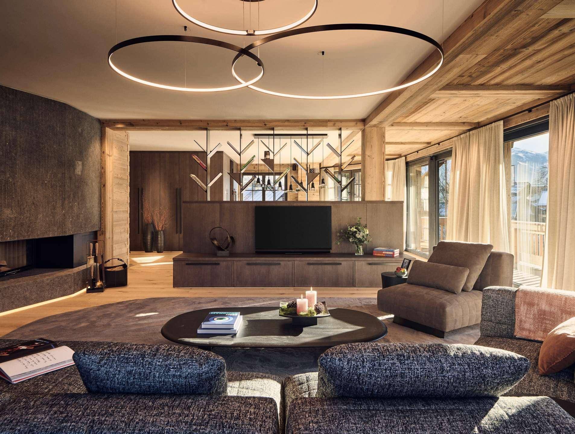 Geräumiges Wohnzimmer mit modernem Kamin, bequemen Sofas und Holzbalkendecke.