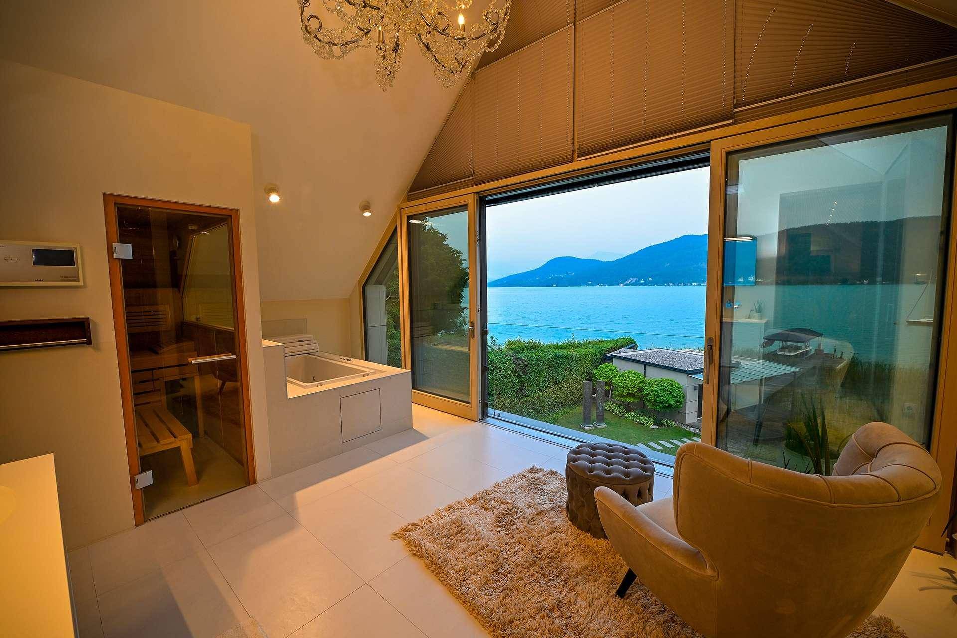 Wellnessbereich mit Sauna, Badewanne und Panoramafenstern mit atemberaubendem See- und Bergblick.