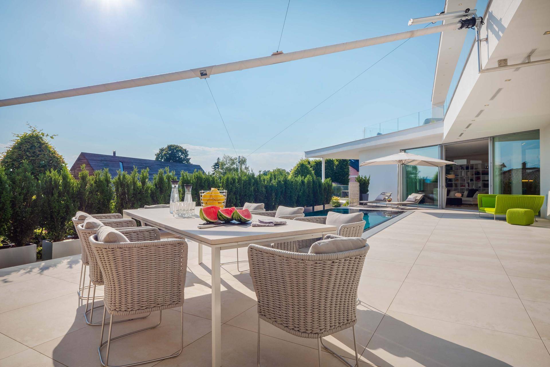 Heller Essbereich im Freien auf einer großzügigen Terrasse mit Blick auf den Pool und die umliegende Landschaft.