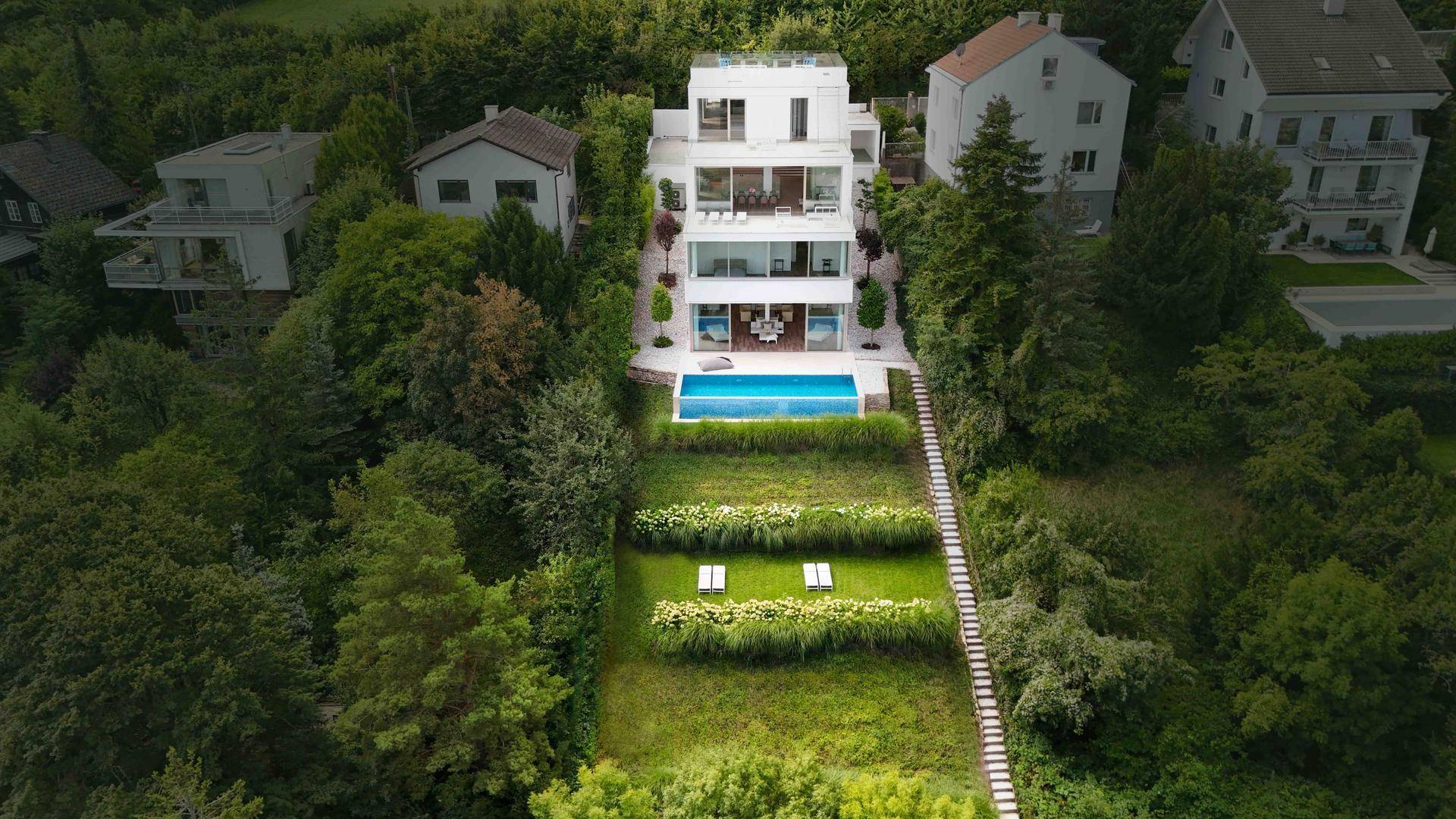 Luftaufnahme der modernen Villa mit weitläufigem Garten, Pool und gepflegten Grünflächen.