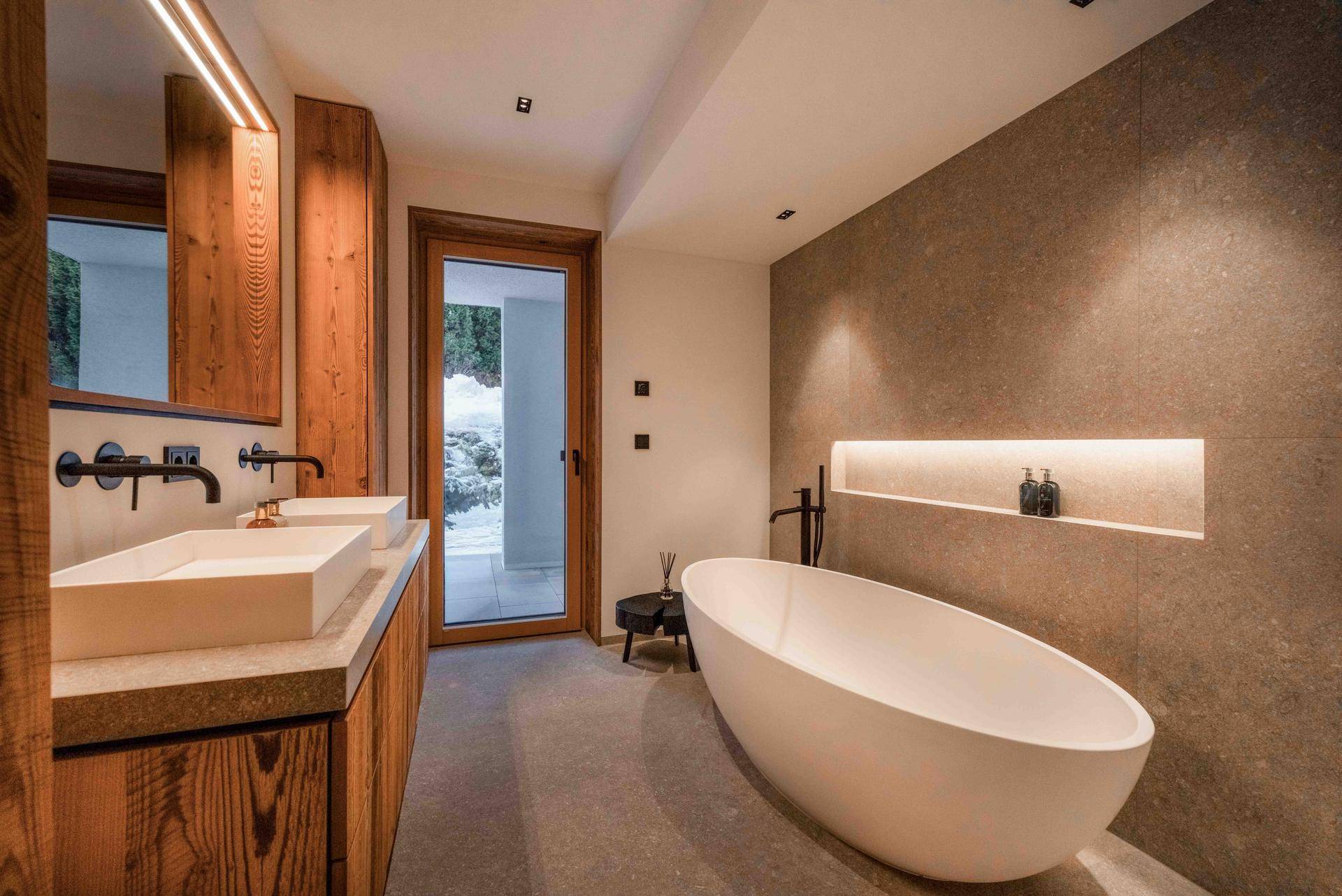 Luxuriöses Badezimmer mit freistehender Badewanne, Doppelwaschbecken und Zugang nach draußen.