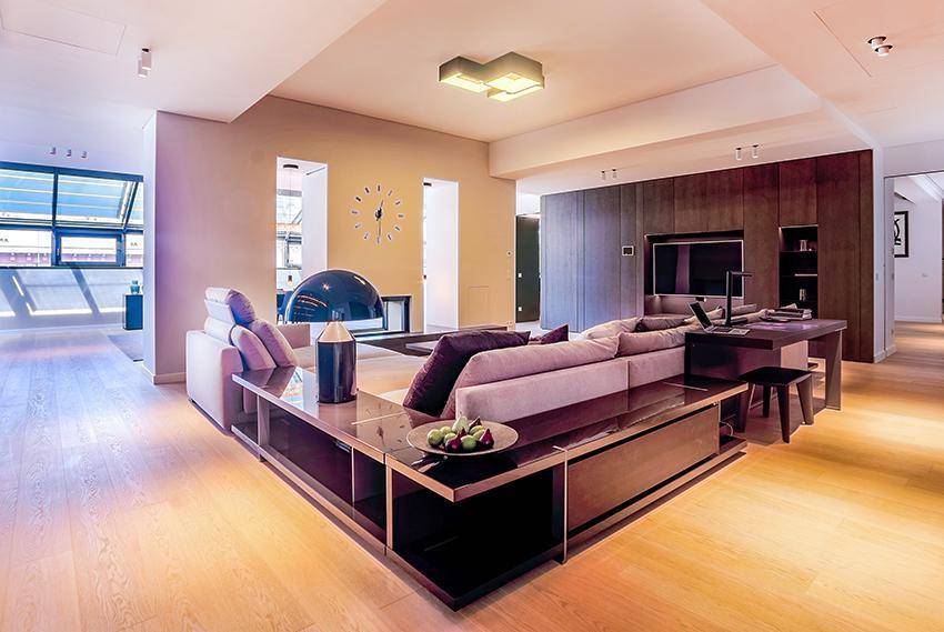 Moderner Wohnbereich mit großem Sofa, Holzboden und integriertem Entertainment-System.