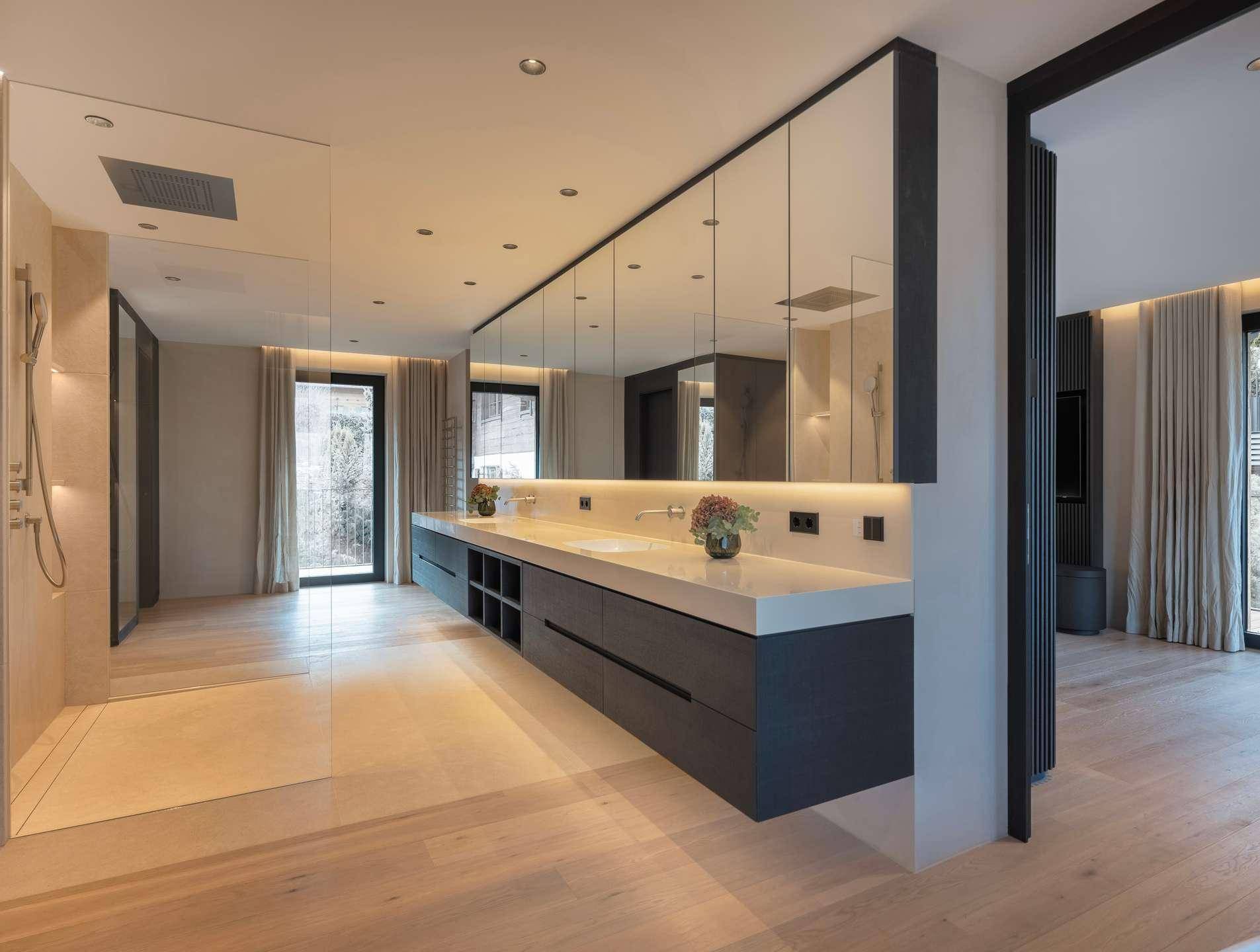 Luxuriöses Badezimmer mit Doppelwaschbecken, großer begehbarer Dusche und Holzboden.