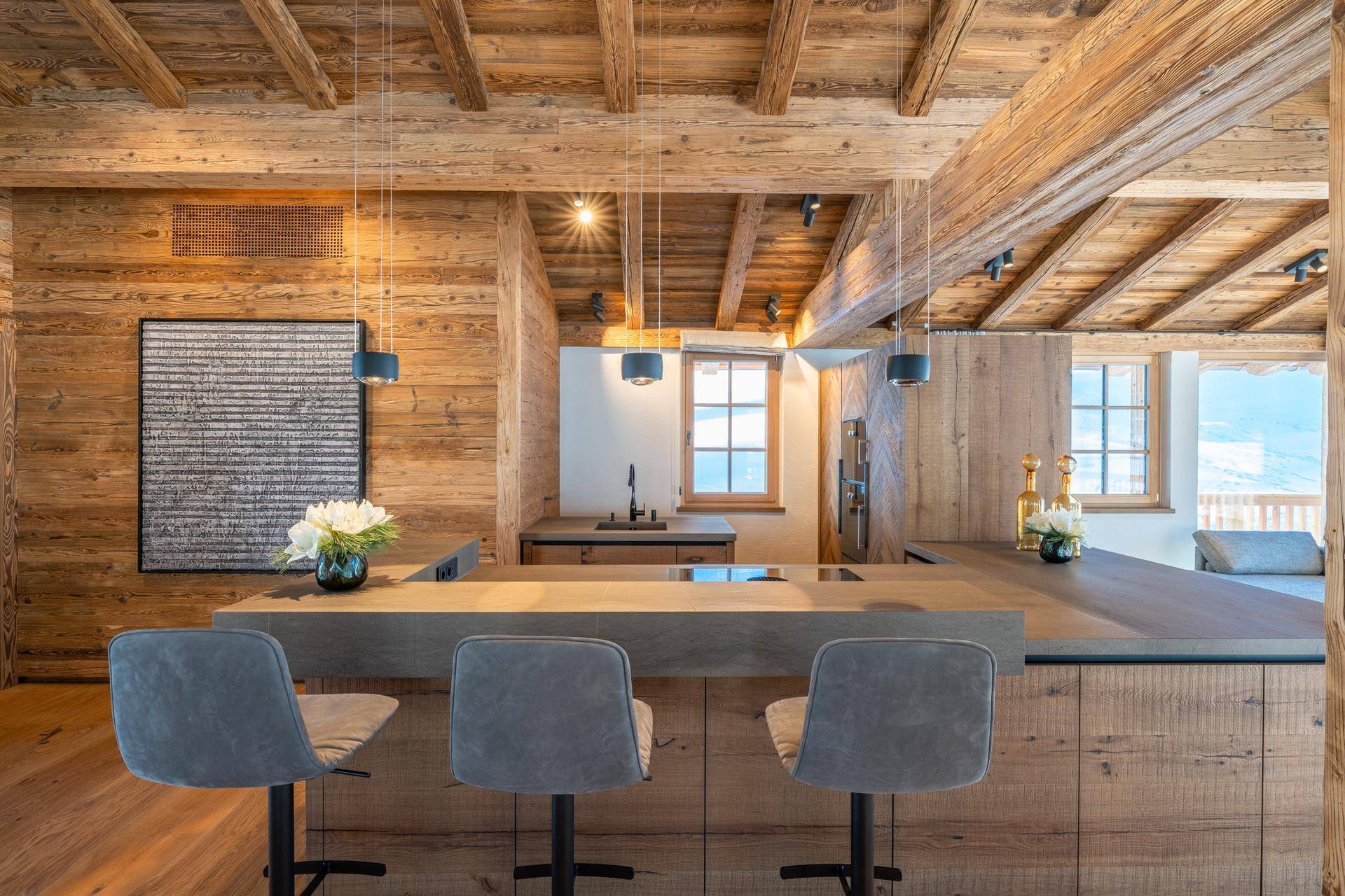 Moderne Holzküche mit Kochinsel, Barhockern und integrierten Geräten im Chalet-Stil.