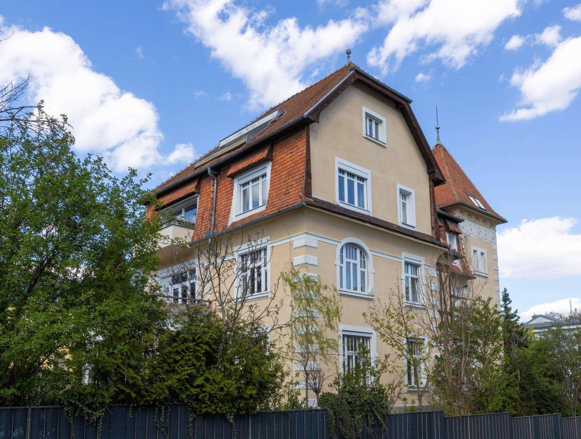 Seitenansicht des historischen Gebäudes mit traditionellem Ziegeldach und großen Fenstern.