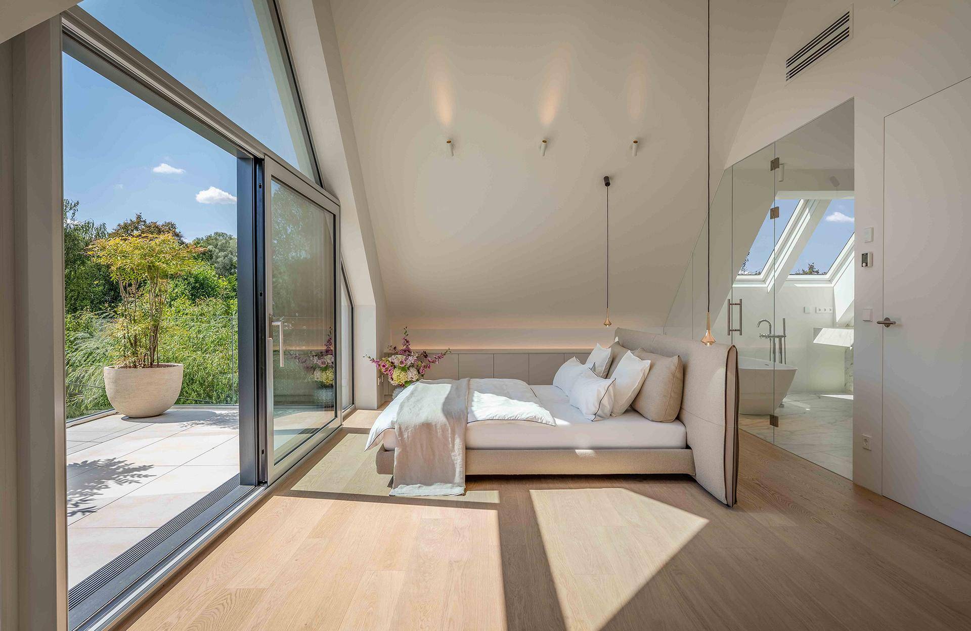 Elegantes Schlafzimmer mit Holzboden, großen Fenstern und offenem Zugang zum luxuriösen Bad.