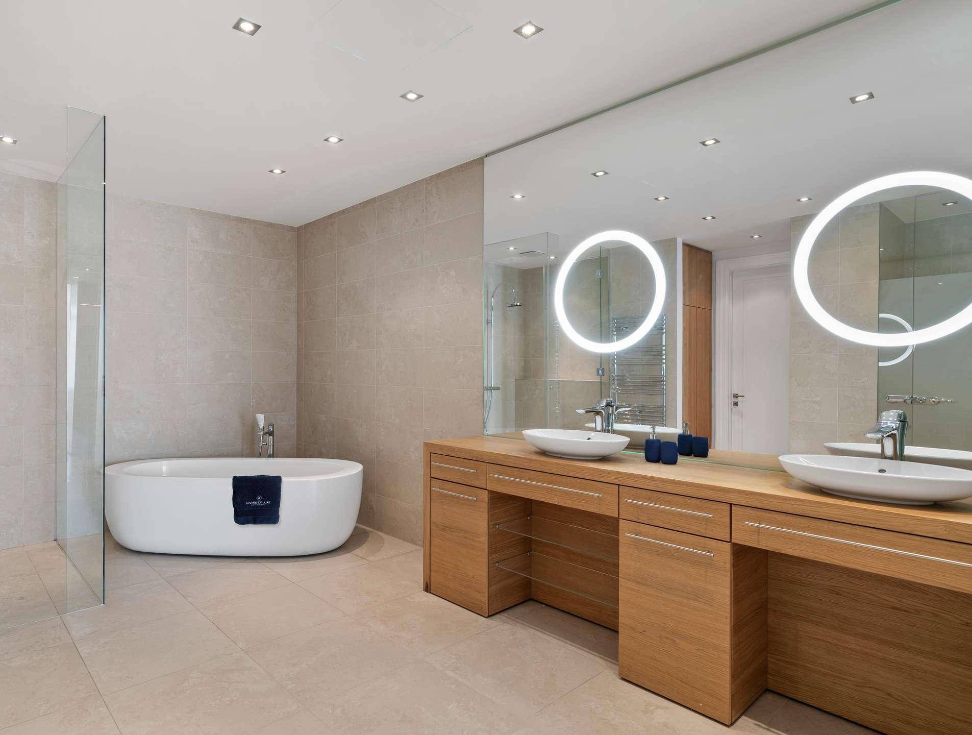 Luxuriöses Badezimmer mit freistehender Badewanne, Doppelwaschbecken und großen Spiegeln.