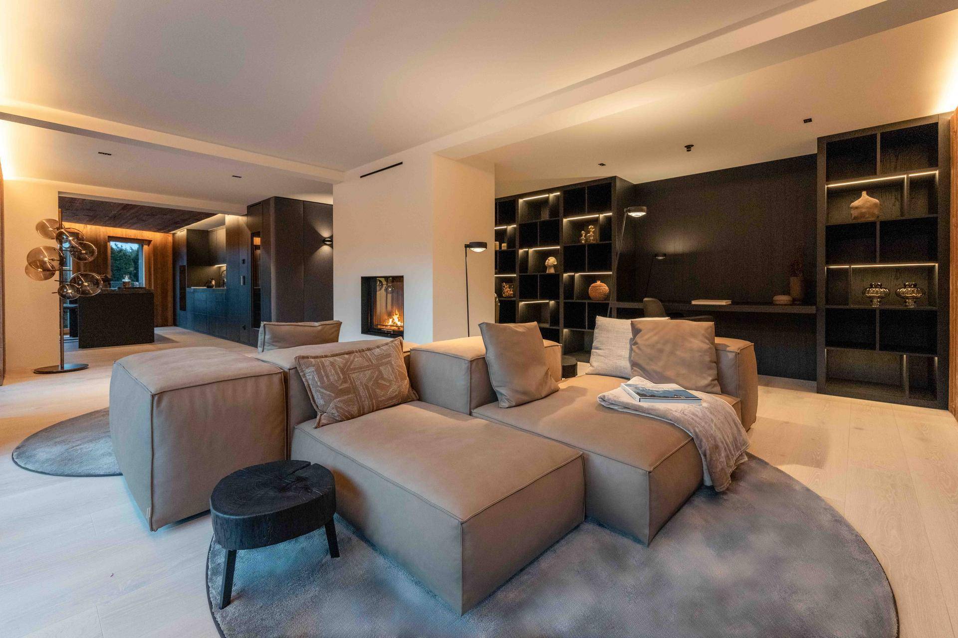 Geräumiges Wohnzimmer mit großem Ecksofa, integrierten Regalen und indirekter Beleuchtung.
