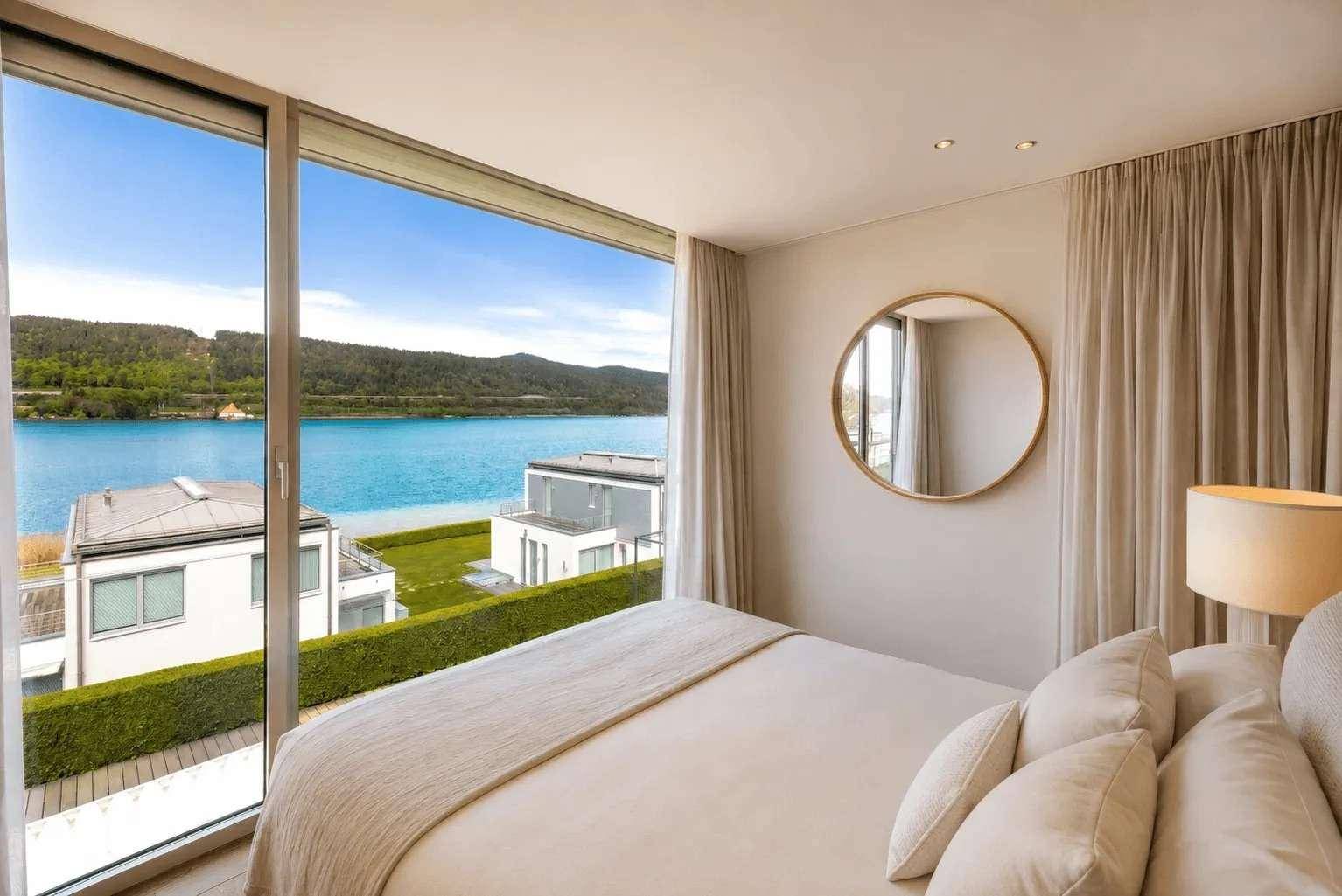 Helles Schlafzimmer mit raumhohen Fenstern, die einen spektakulären Blick auf den See bieten.