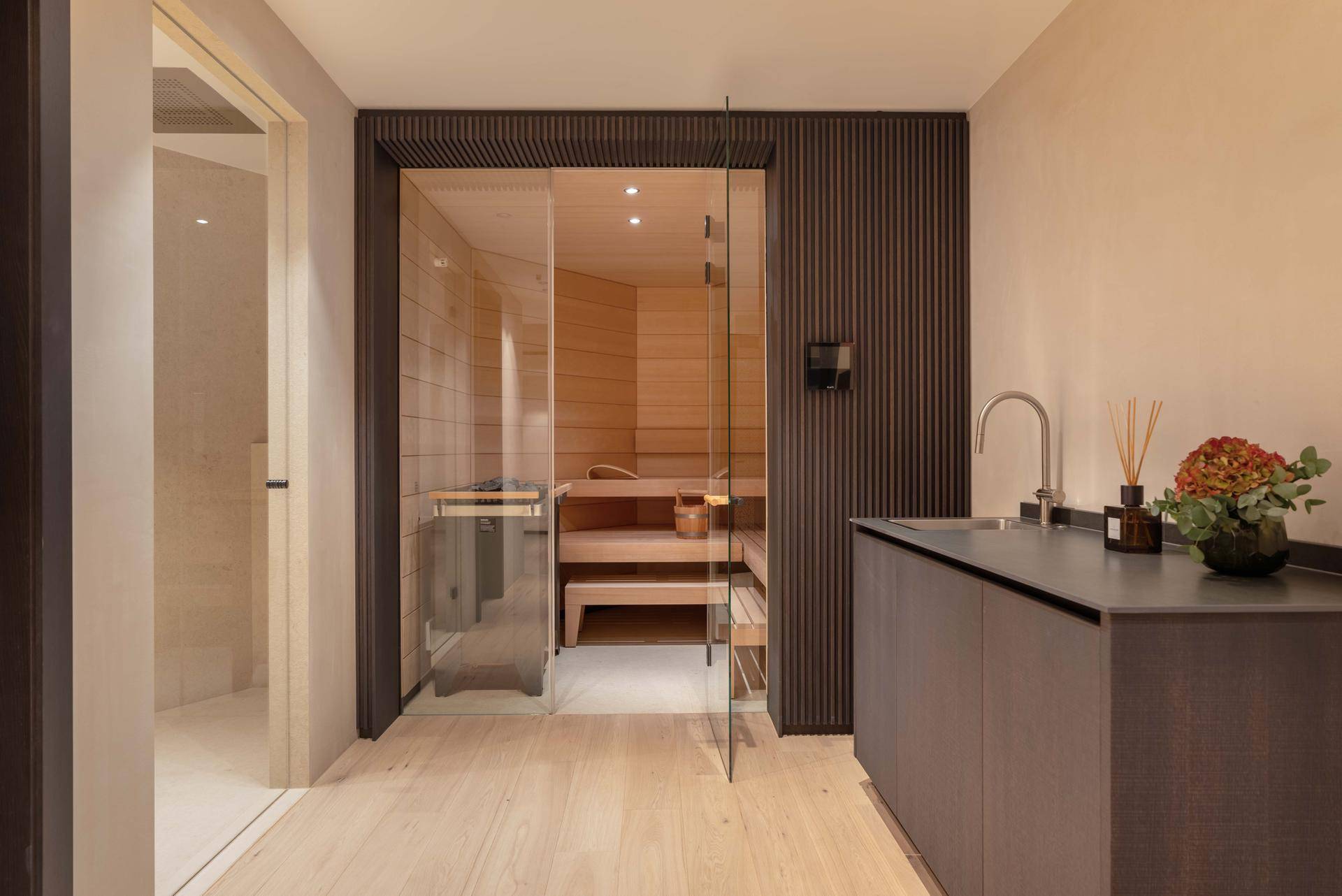 Exklusiver Wellnessbereich mit moderner Sauna, Waschbecken und stilvoller Holzverkleidung.