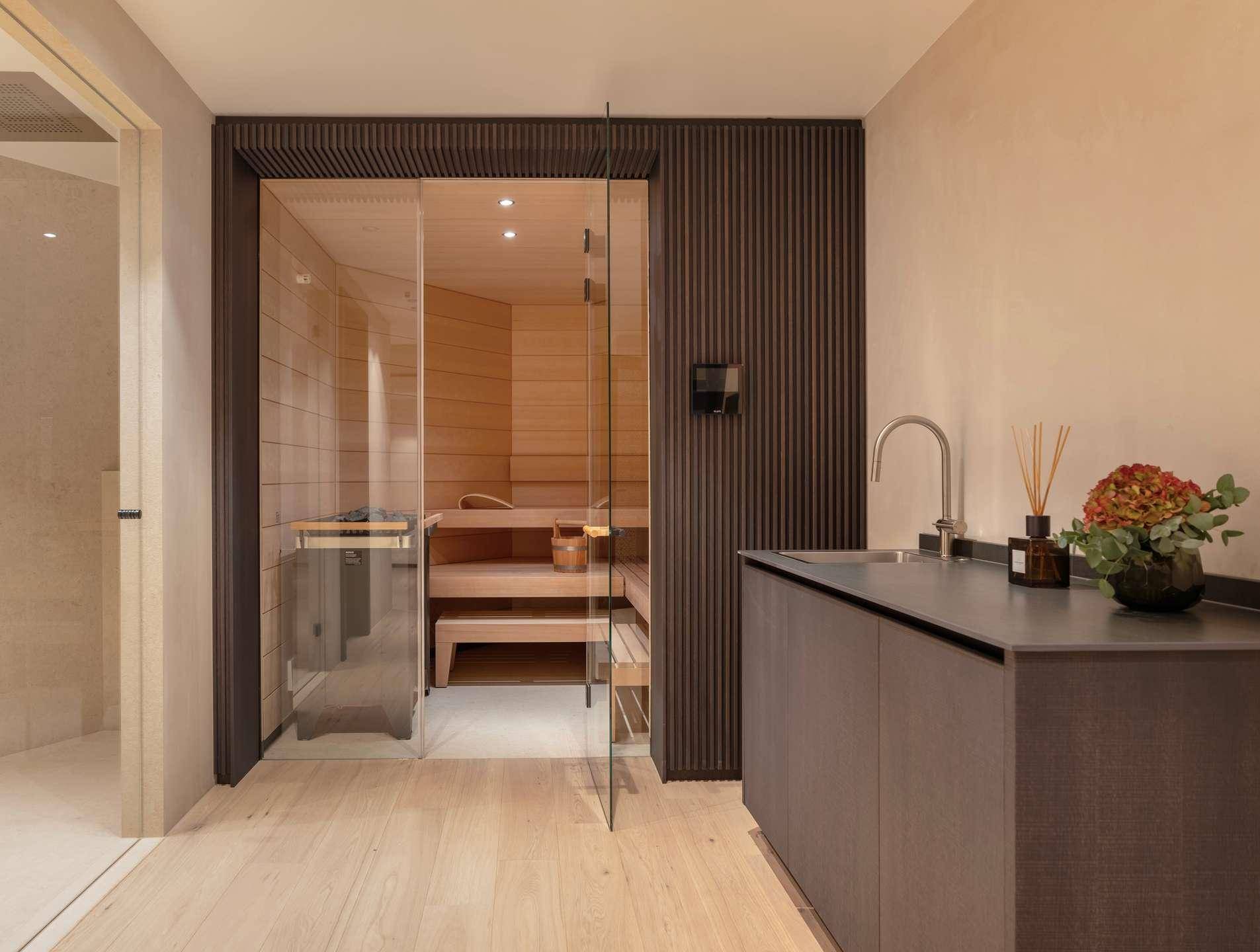 Moderner Wellnessbereich mit Sauna und Waschbecken in hellem Holzdesign.