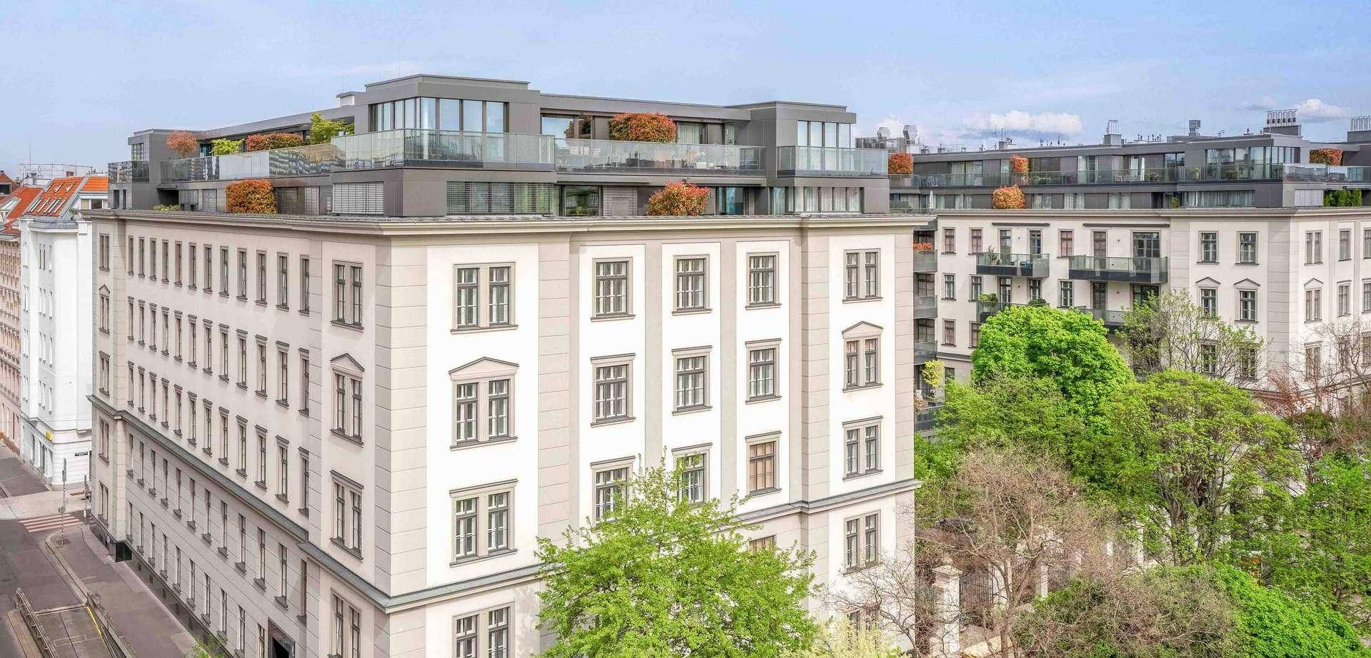 Moderne Wohngebäude mit Dachterrassen und grünen Bepflanzungen in urbaner Umgebung.