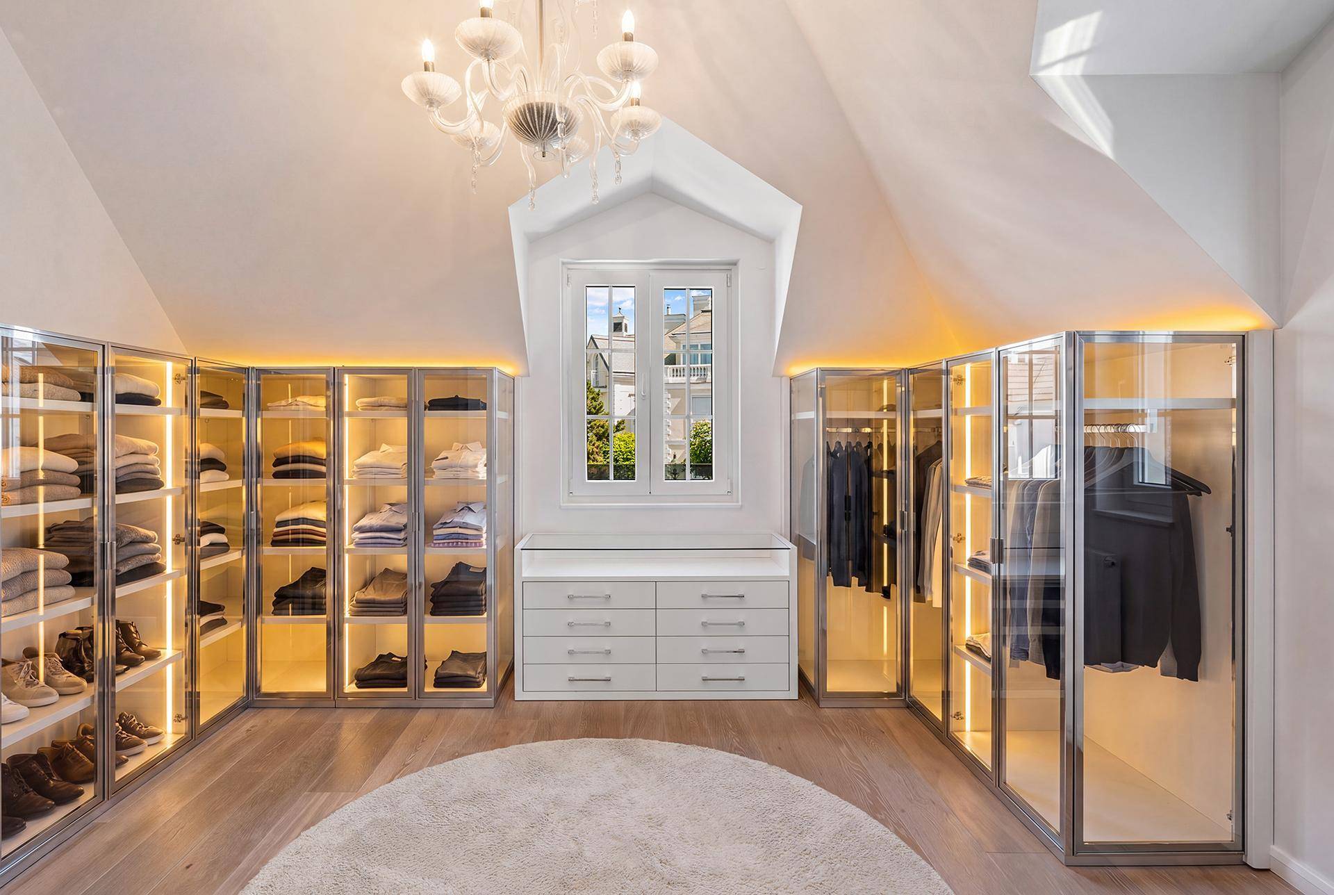 Geräumiger begehbarer Kleiderschrank mit integrierter Beleuchtung und viel Stauraum.