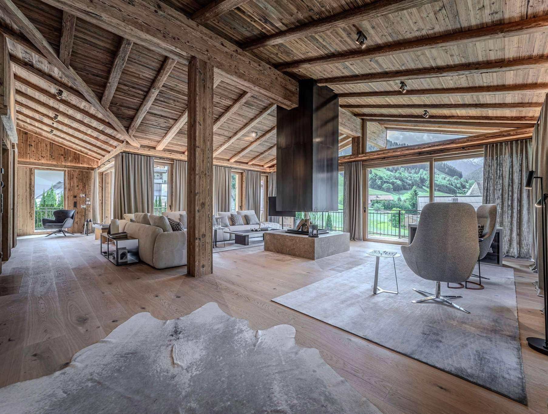 Geräumiges Wohnzimmer im alpinen Stil mit Holzbalken, Kamin und Bergblick.