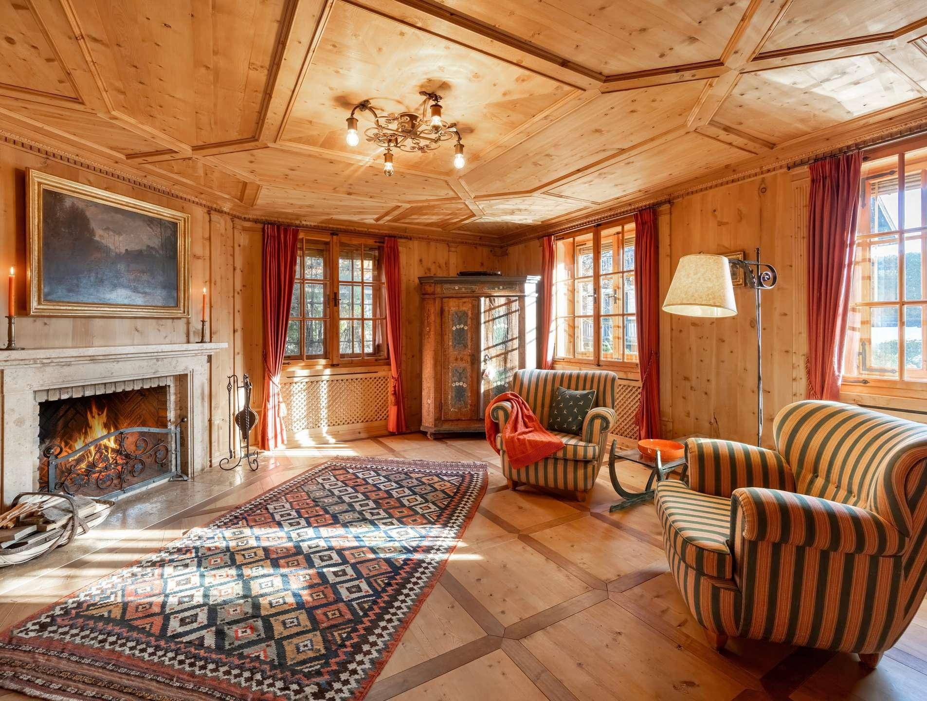 Gemütliches Wohnzimmer mit Holztäfelung, offenem Kamin und traditionellem Teppich.