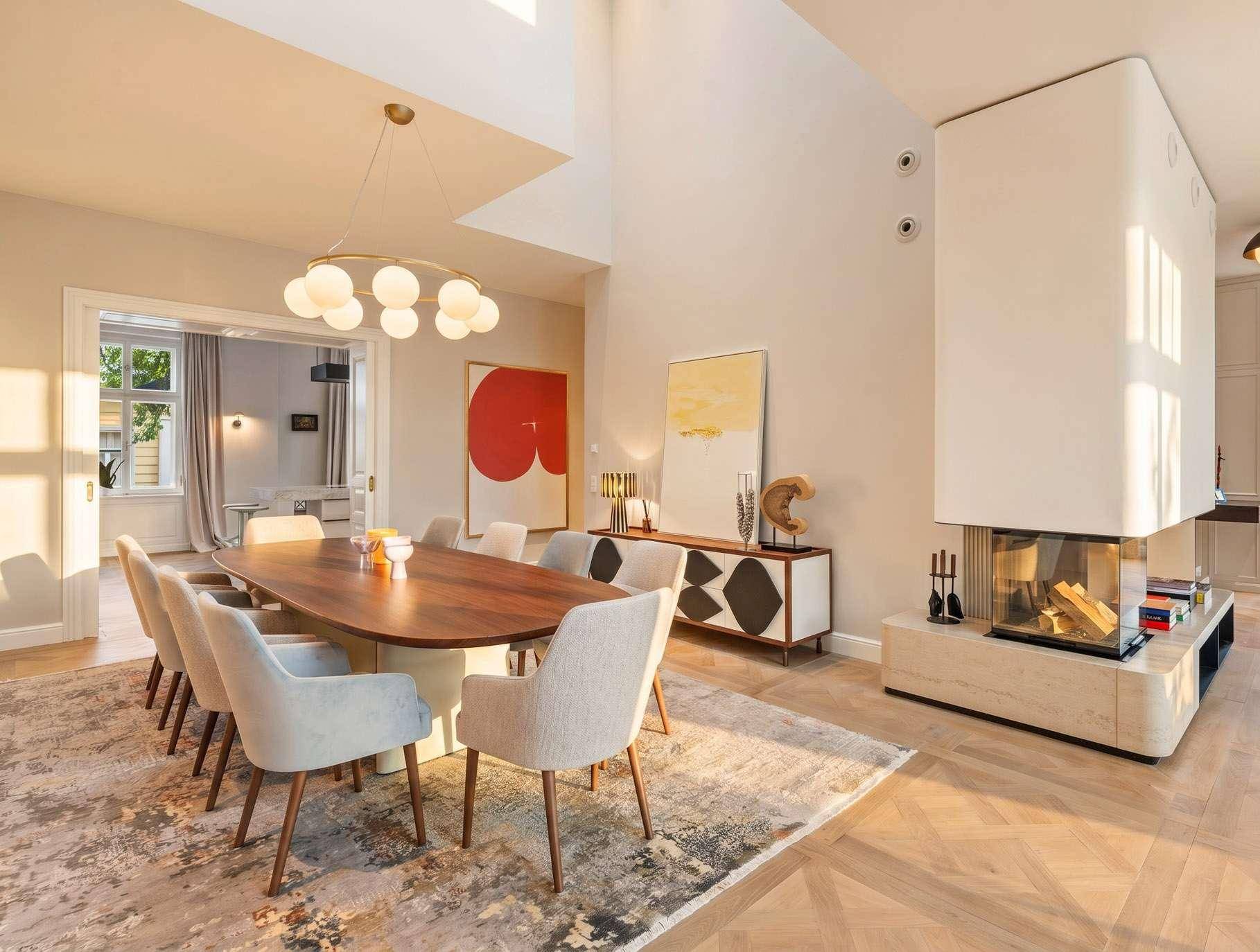 Eleganter Essbereich mit großem Holztisch, modernem Kamin und Kunstwerken an den Wänden.