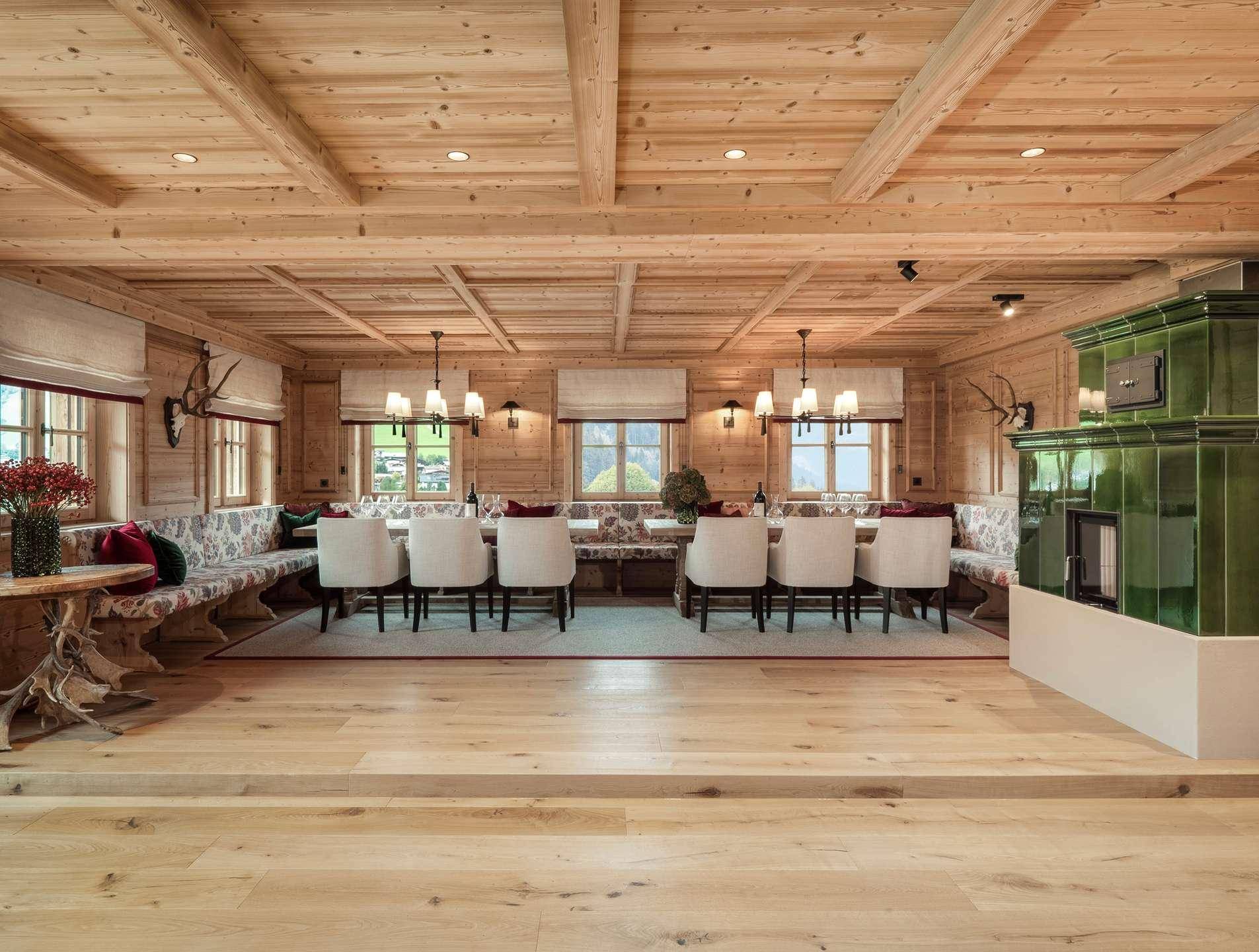 Traditioneller Essbereich im Chalet-Stil mit grünem Kachelofen, Holzwänden und Bergblick.