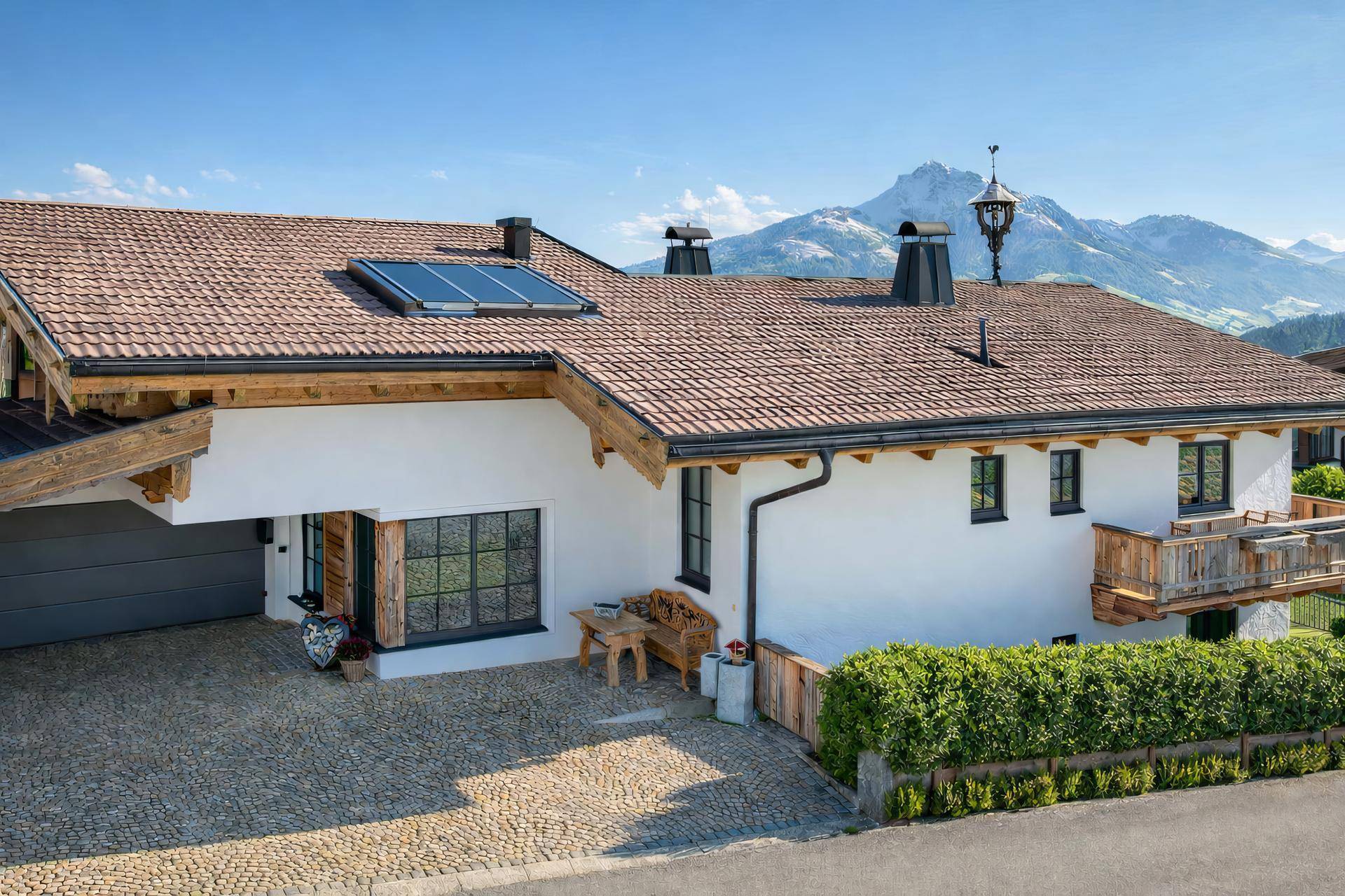 Alpenländisches Haus mit Satteldach, Solaranlage und gepflasterter Einfahrt.