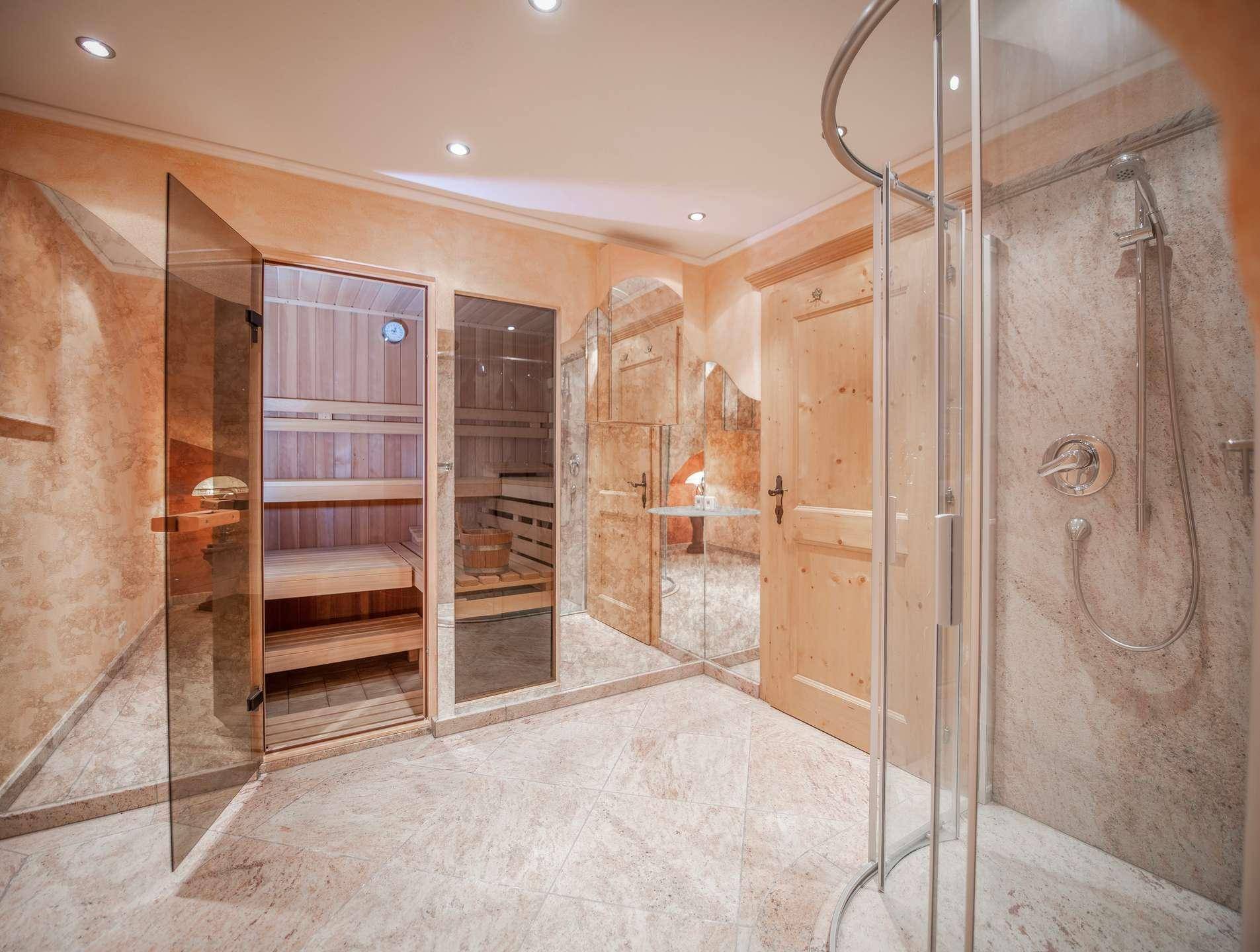Geräumiges Badezimmer mit integrierter Sauna und moderner Glasdusche, ideal für Entspannung und Wellness.