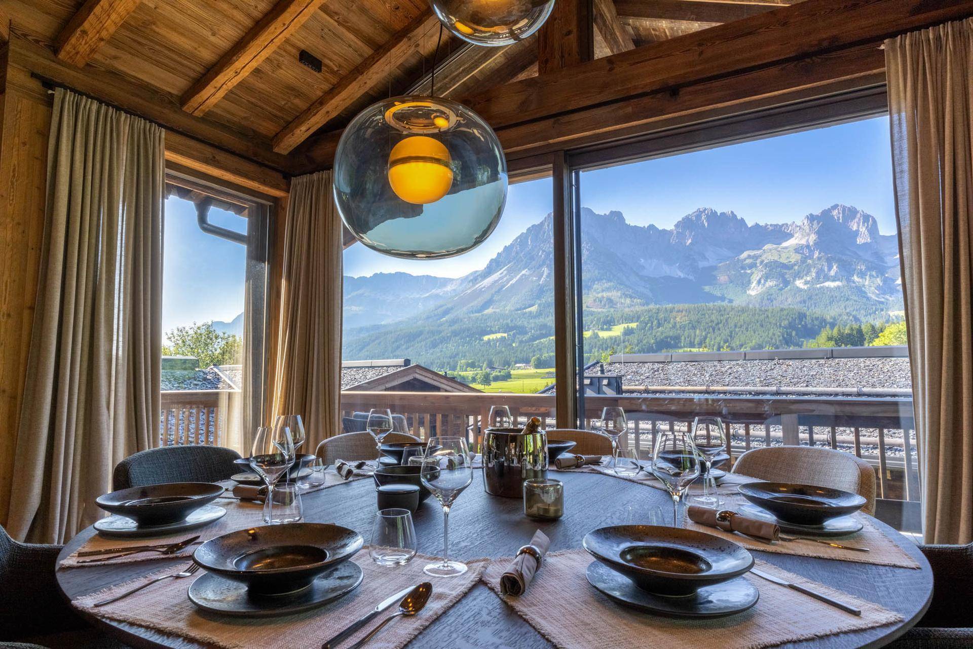 Heller Essbereich mit Panoramablick auf die Berge und hochwertiger Tischdekoration.