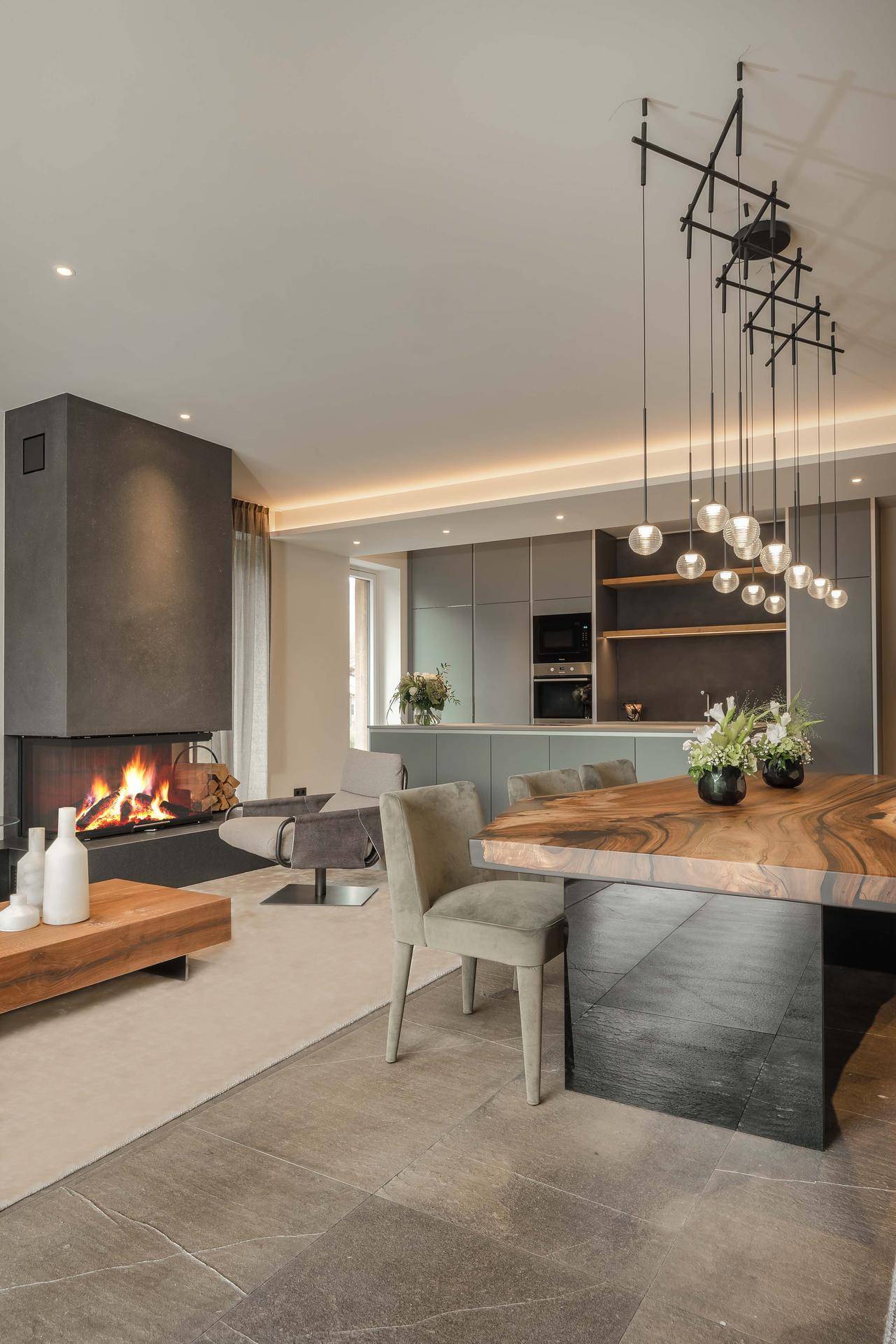 Eleganter Wohn- und Essbereich mit modernem Kamin, Holztisch und stilvoller Beleuchtung.