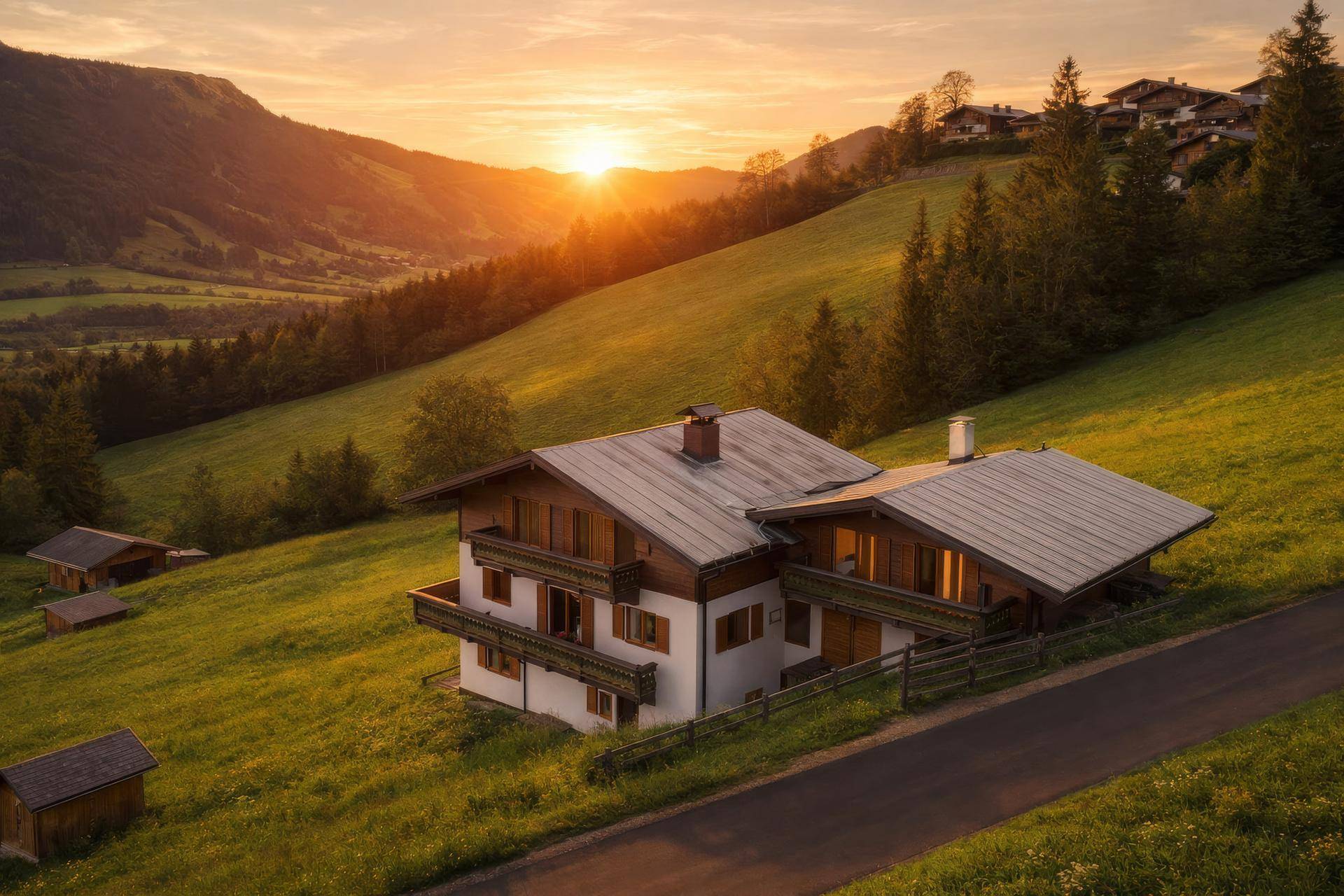 Charmantes Haus auf einem grünen Hang im goldenen Licht des Sonnenuntergangs mit Bergblick.