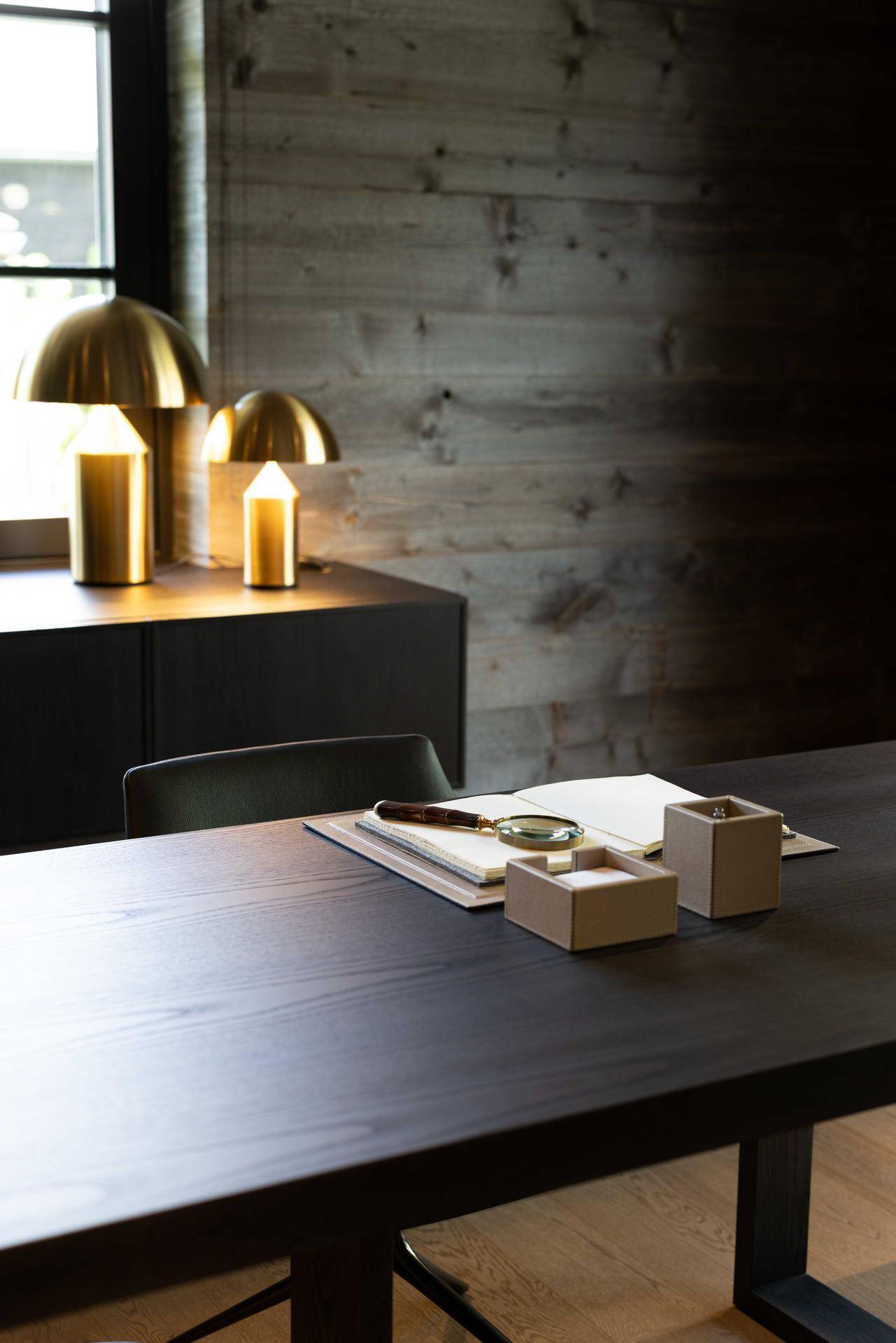 Detailaufnahme eines Schreibtisches mit goldenen Lampen und Holzvertäfelung.