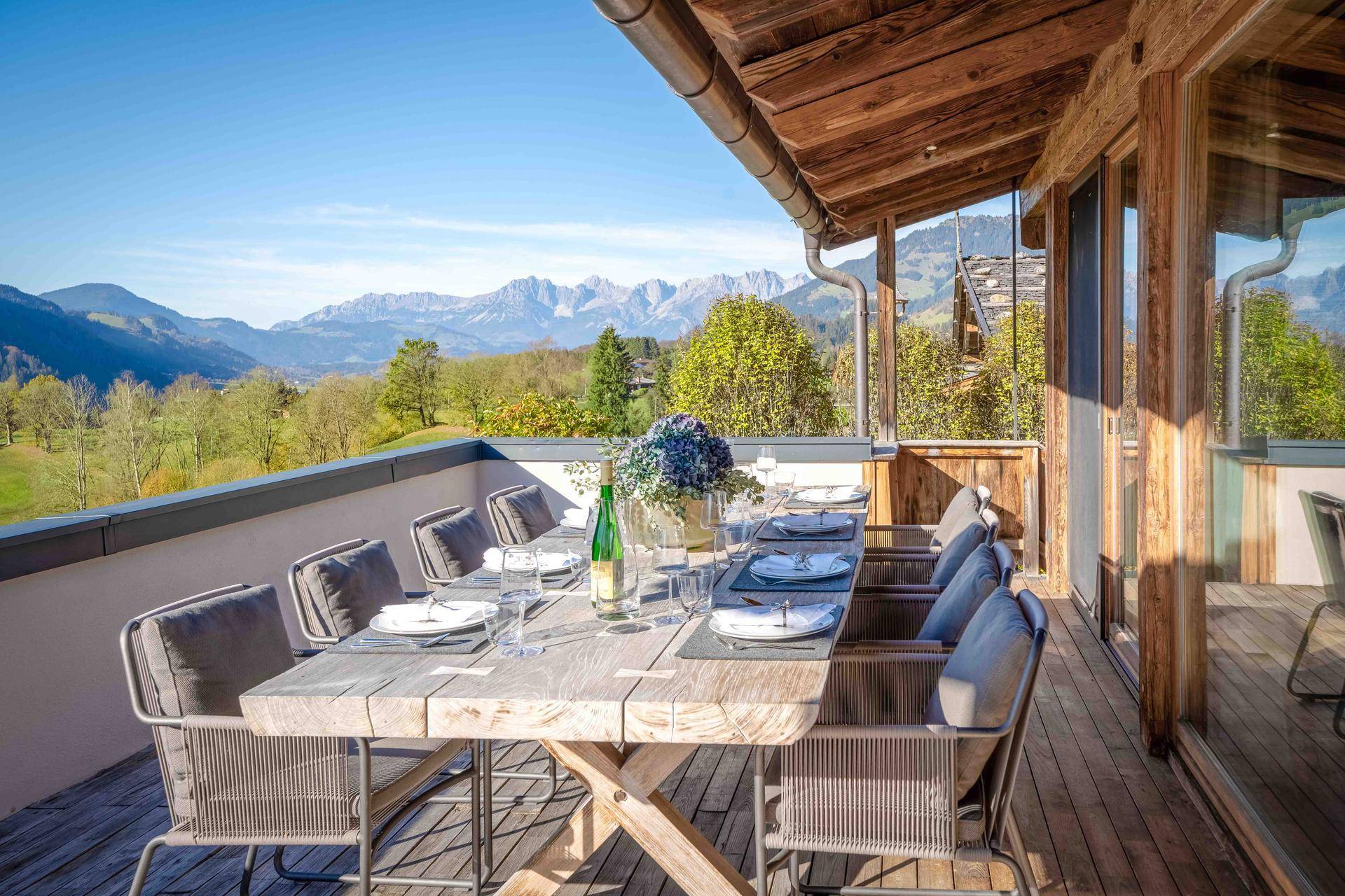 Große überdachte Terrasse mit Esstisch und Stühlen, ideal für Mahlzeiten im Freien mit Bergblick.