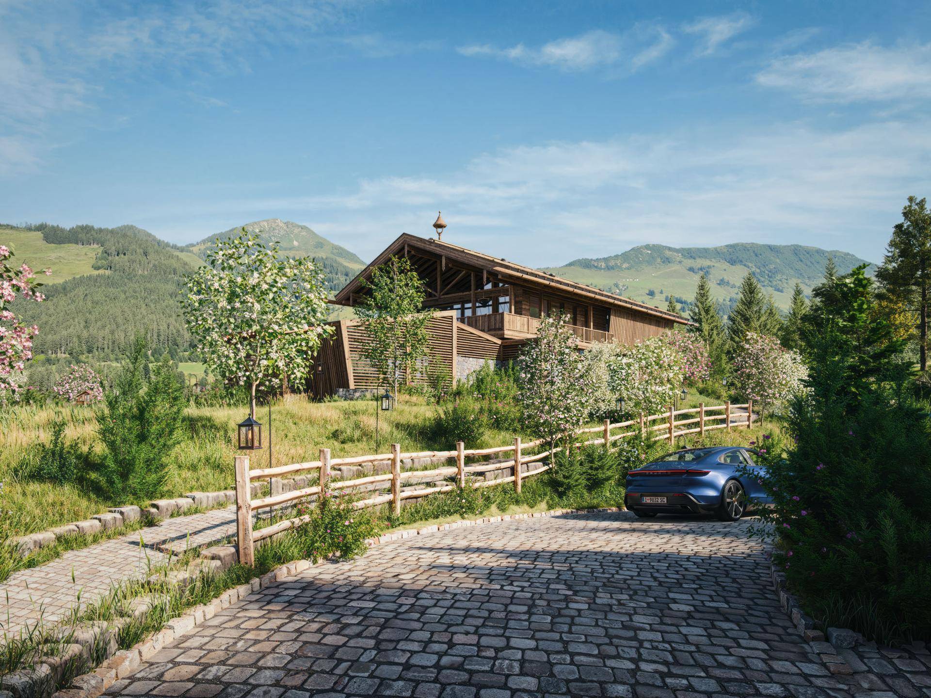 Zufahrt zum modernen Chalet mit Kopfsteinpflaster und traditionellem Holzzaun in grüner Umgebung.