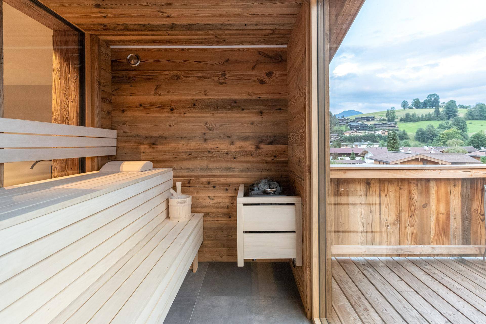Private Sauna mit Holzbänken und Panoramablick auf die grüne Berglandschaft.