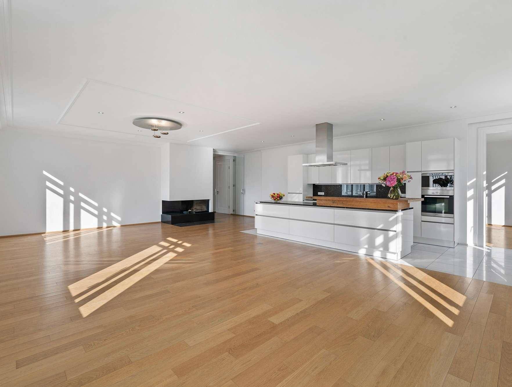 Geräumiger offener Wohnbereich mit integrierter Küche, Kamin und Holzboden.