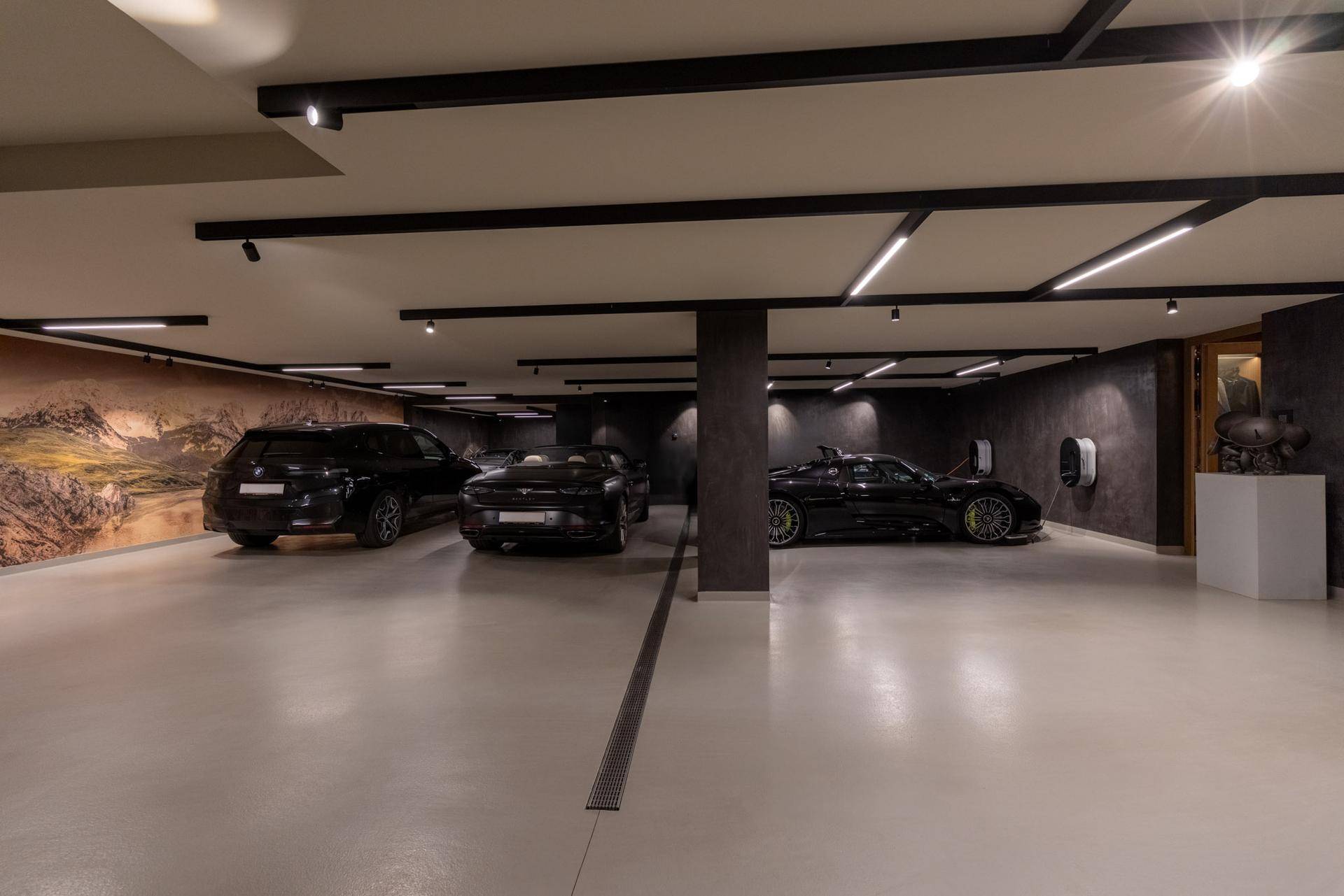 Geräumige Tiefgarage mit mehreren Stellplätzen, luxuriösen Fahrzeugen und Ladestationen für Elektroautos.