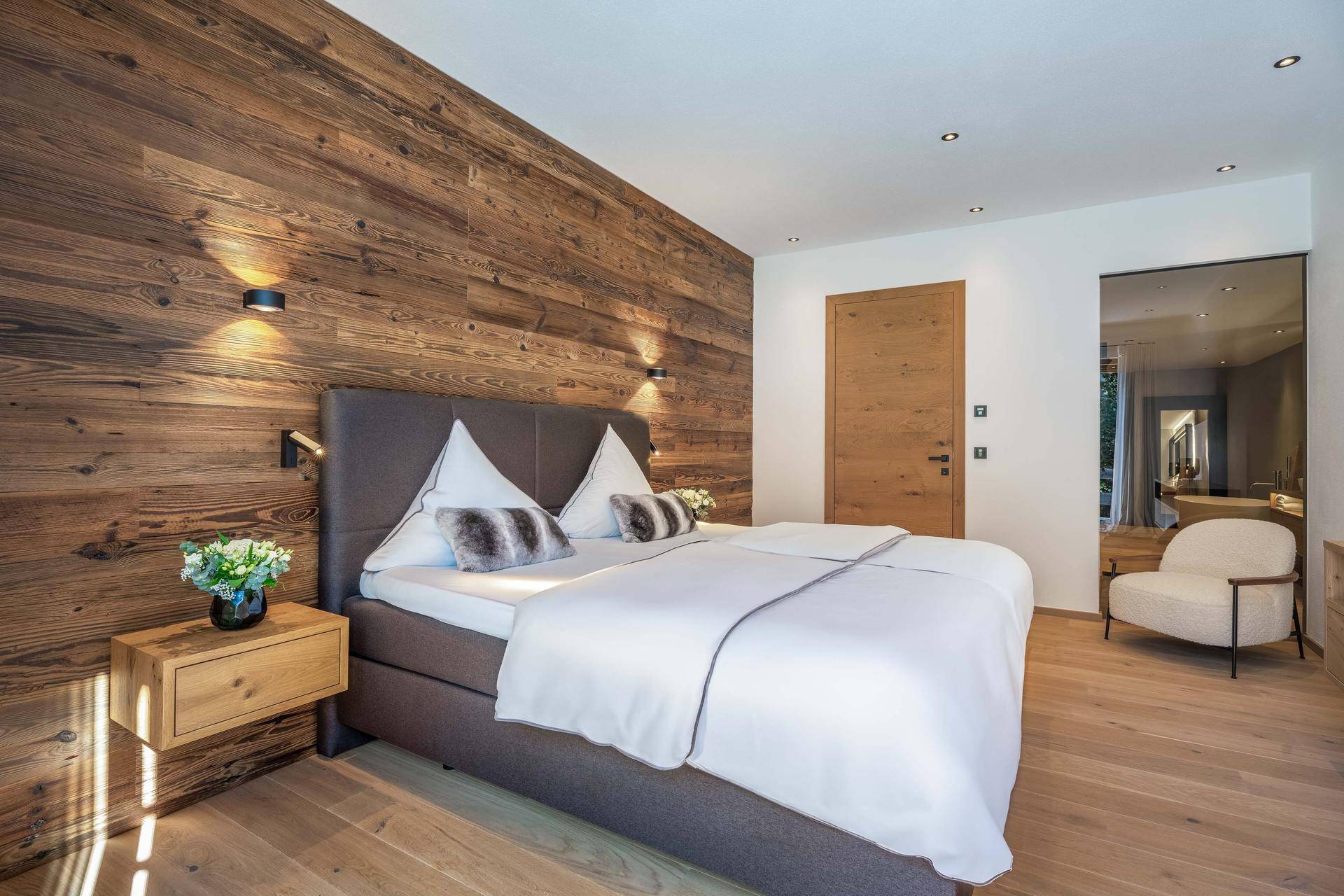 Gemütliches Schlafzimmer mit Holzwand, Doppelbett und indirekter Beleuchtung für eine warme Atmosphäre.