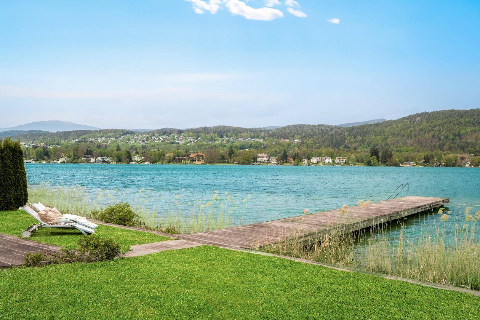 Privater Seezugang mit Holzsteg und Liegestuhl, ideal zum Entspannen am Ufer des klaren Sees.