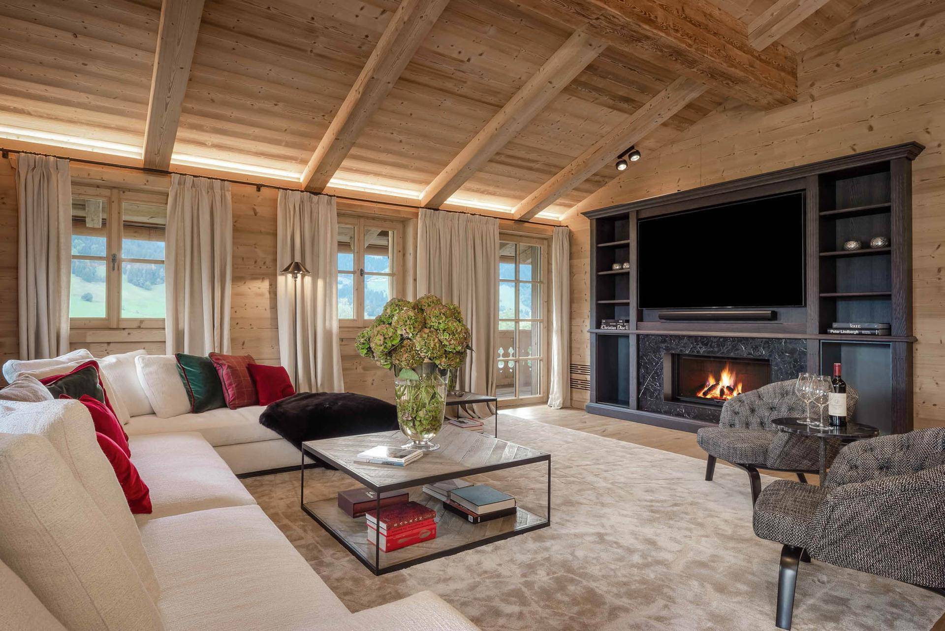 Gemütliches Wohnzimmer mit Kamin, großem Sofa und Holzwänden unter einer Dachschräge.