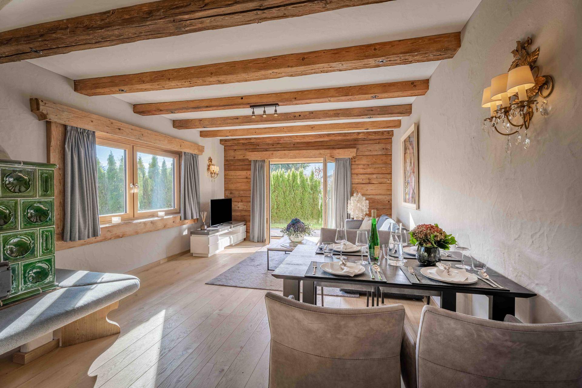Heller Wohn-Essbereich mit Holzbalken, großem Esstisch und Zugang zur Terrasse mit Gartenblick.