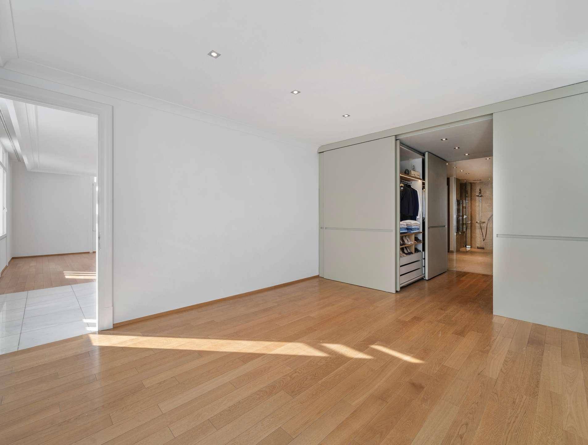 Schlafzimmer mit Holzboden und Schiebetüren, die zu einem begehbaren Kleiderschrank führen.