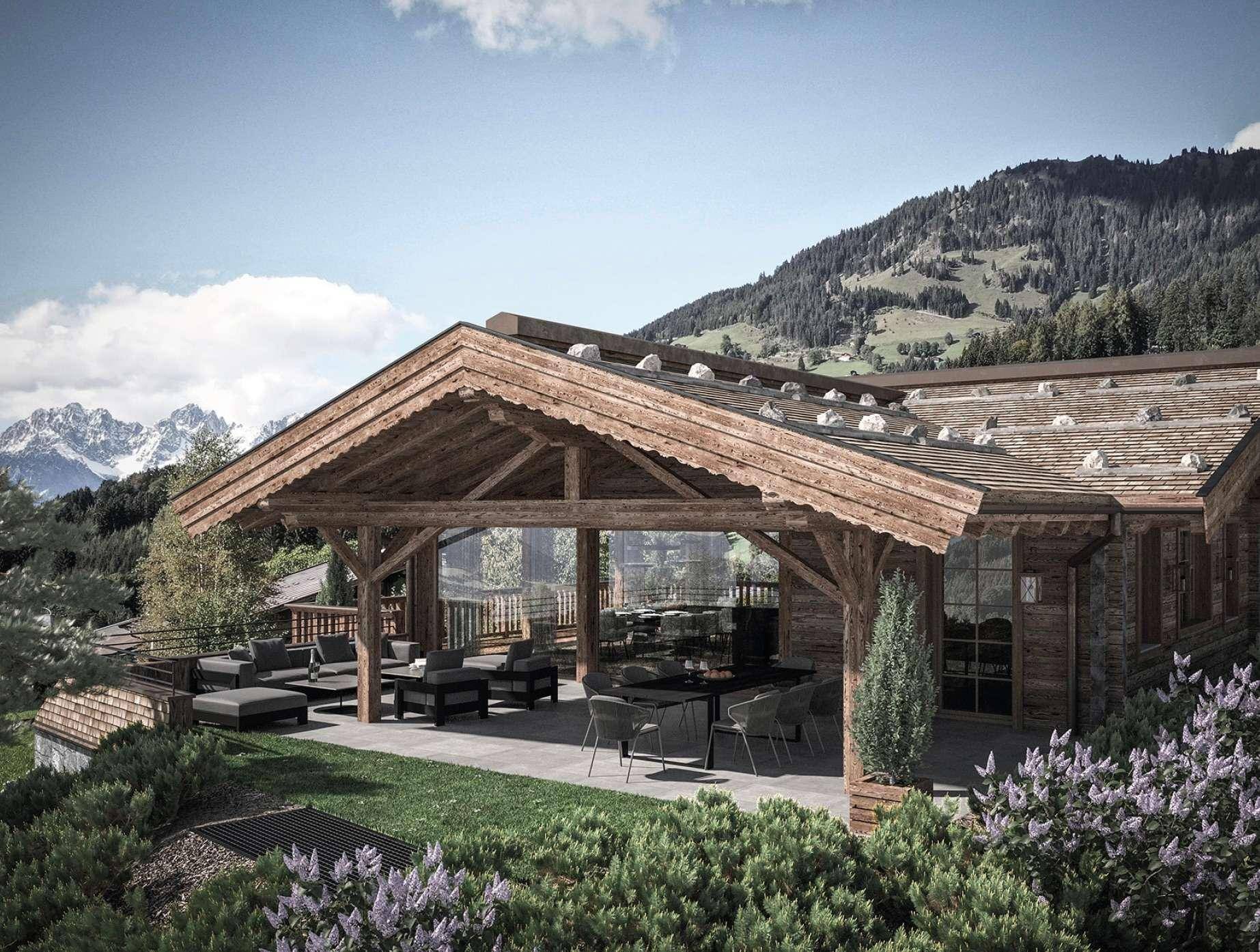 Überdachte Terrasse mit bequemen Lounge-Möbeln und Esstisch, umgeben von alpiner Landschaft.