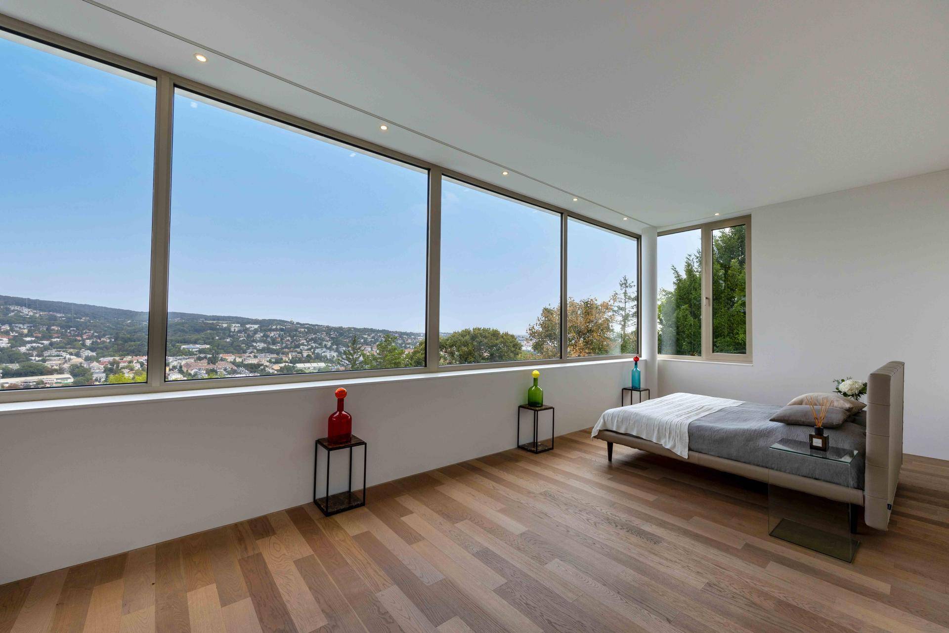 Schlafzimmer mit großen Panoramafenstern, die einen weiten Blick über die grüne Landschaft bieten.