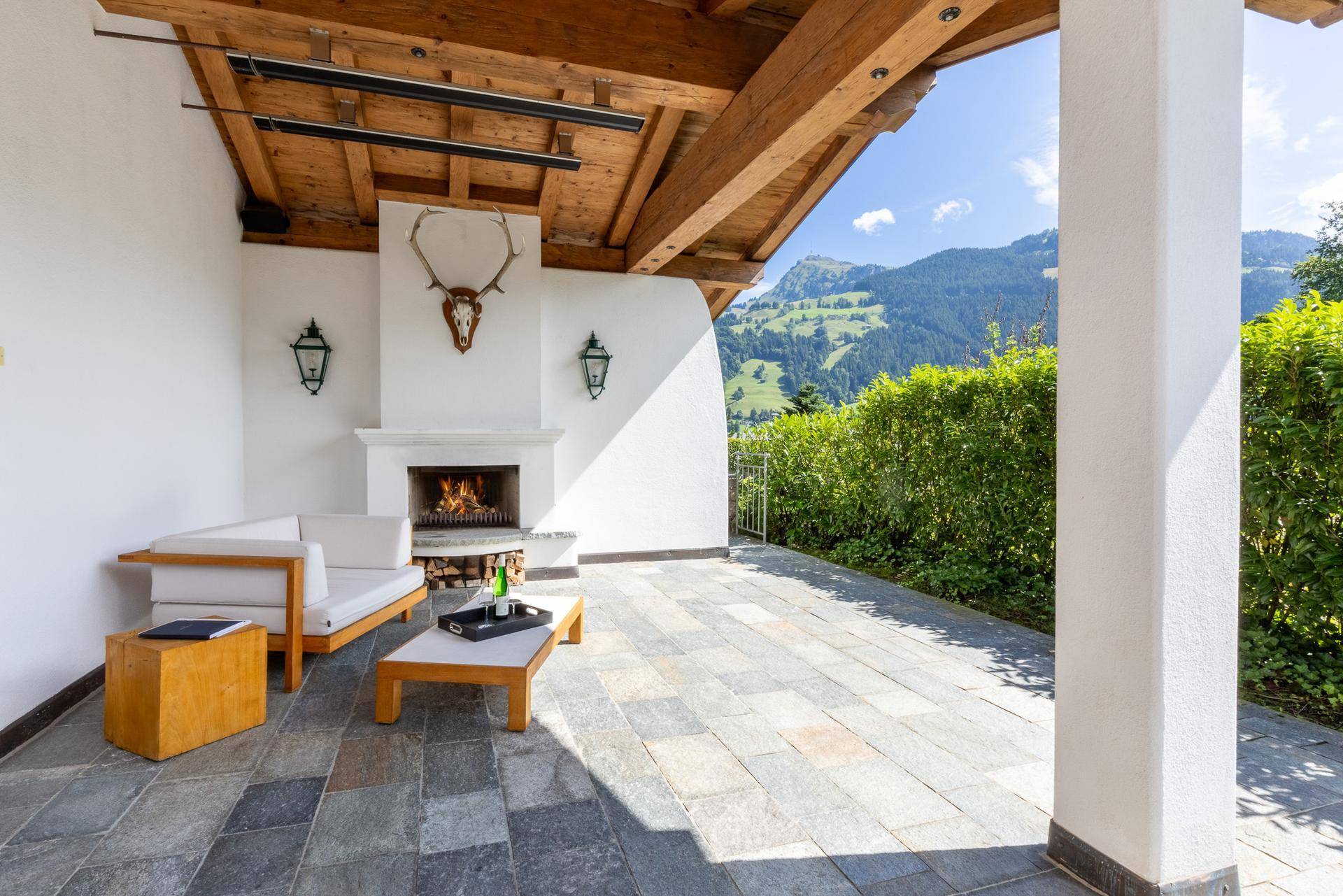 Überdachte Terrasse mit Außenkamin, gemütlicher Sitzecke und herrlichem Bergblick.
