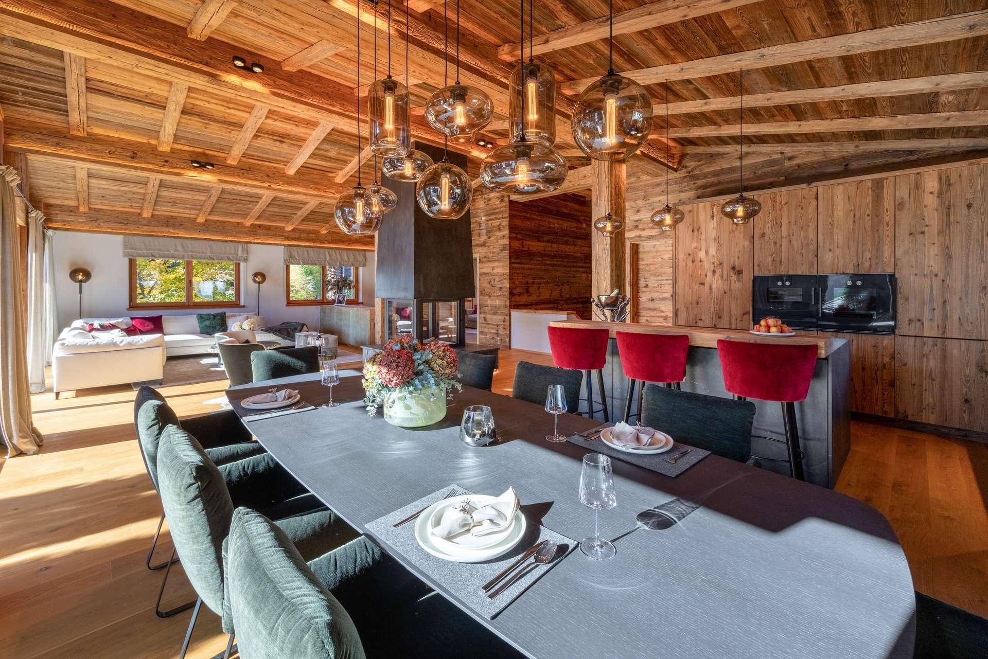 Eleganter Essbereich mit langer Tafel und Designer-Pendelleuchten, offen zur Küche und zum Wohnbereich.