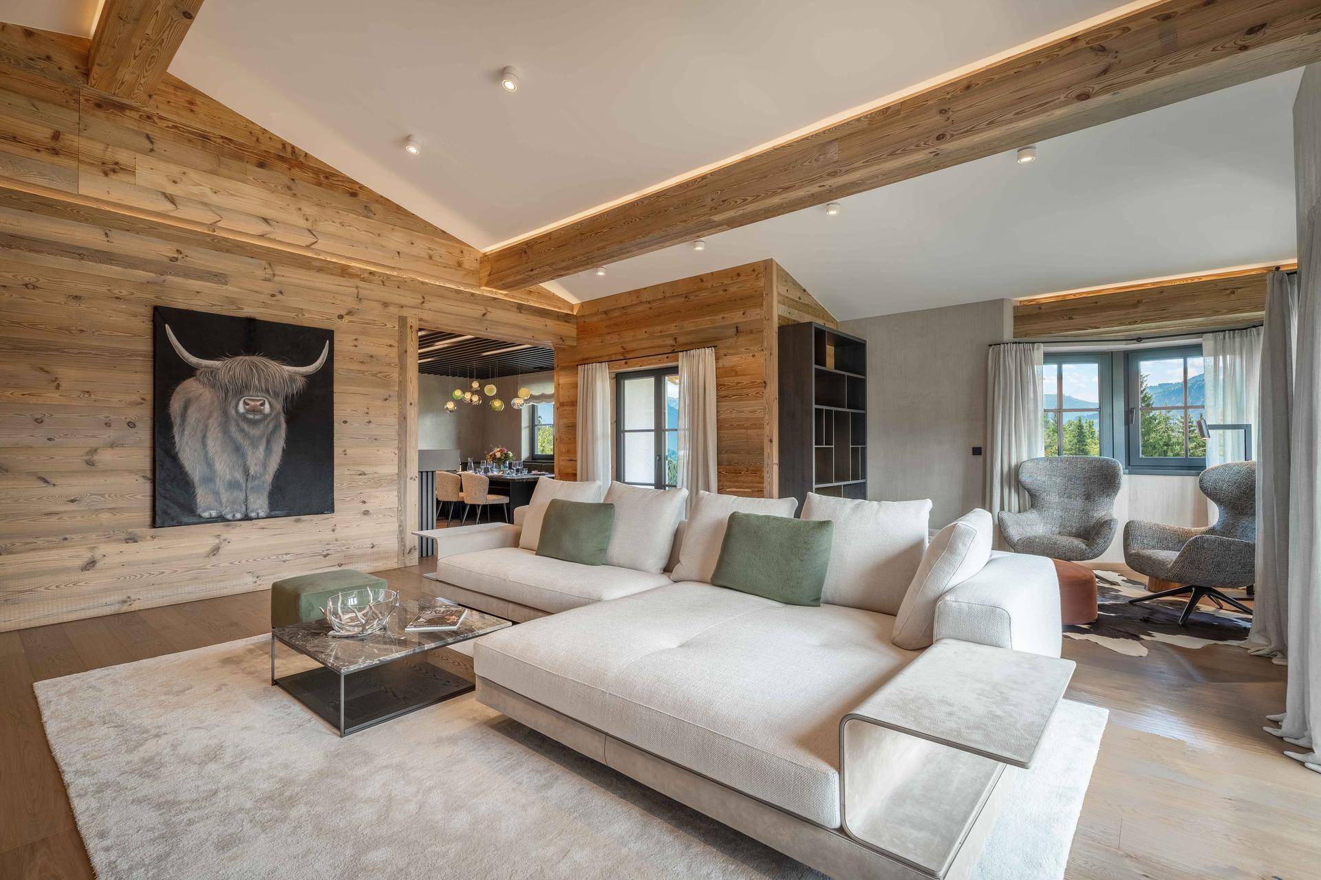 Gemütliches Wohnzimmer mit großem Sofa, Holzwänden und Blick in den Essbereich.